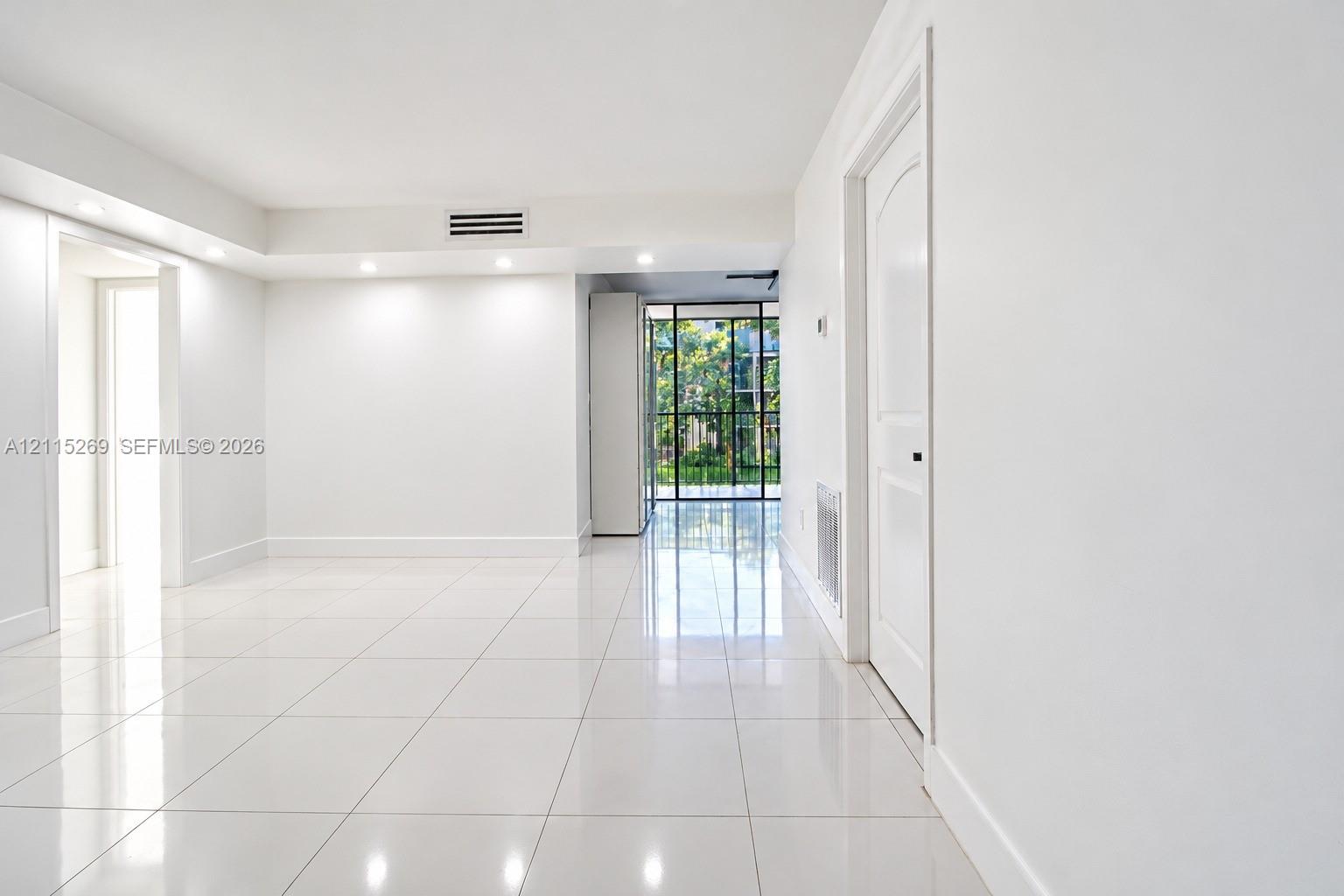 Glossy tile flooring, recessed lighting, white interior walls, solid-core interior doors, and floor-to-ceiling multi-pane window featuring exterior greenery