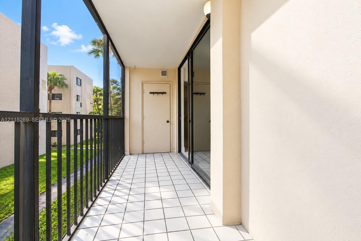 Screened-in balcony featuring tile flooring, metal railing, and a private storage closet
