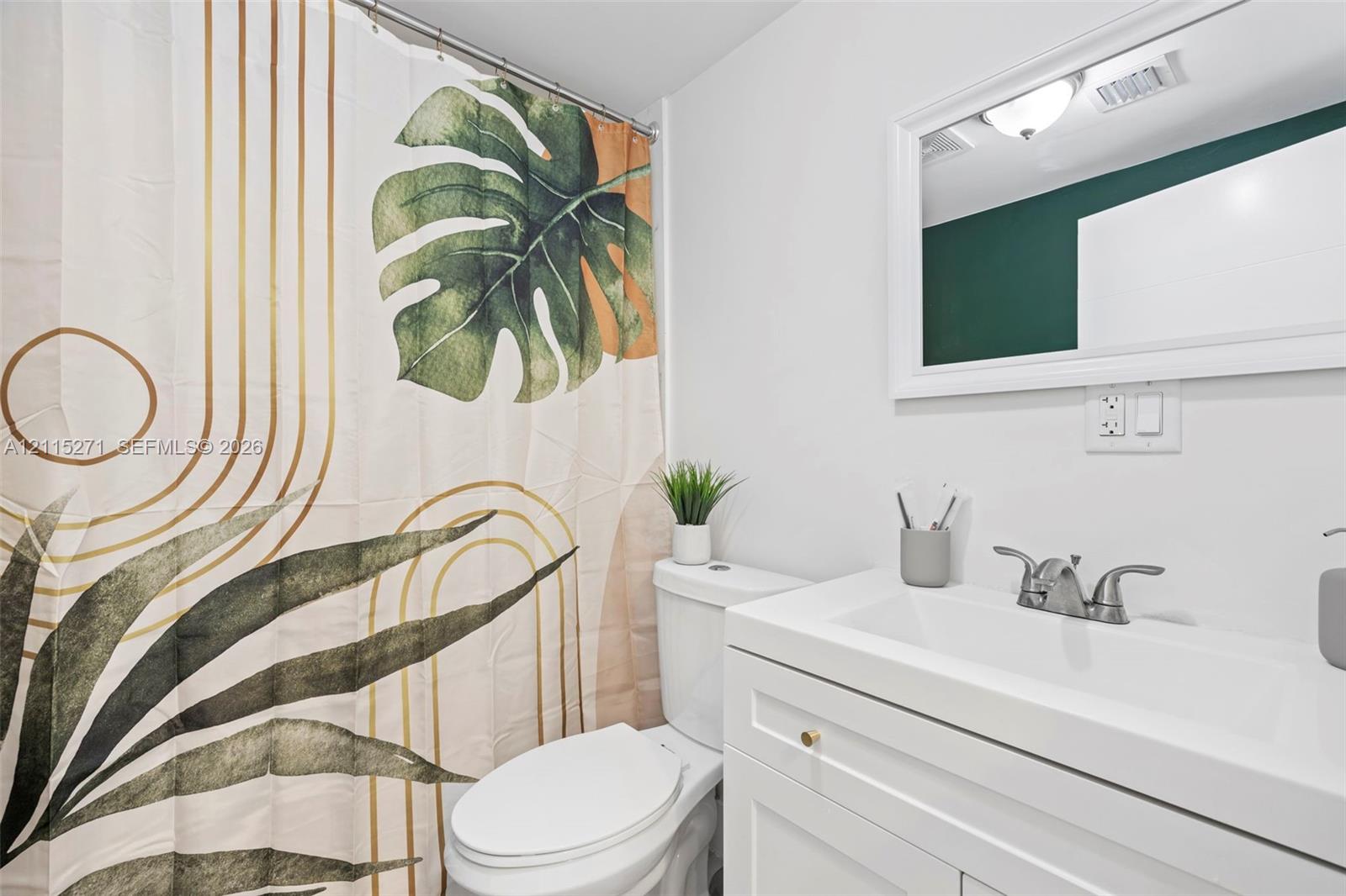 White vanity featuring a rectangular basin, metallic dual-handle faucet, and framed wall-mounted mirror