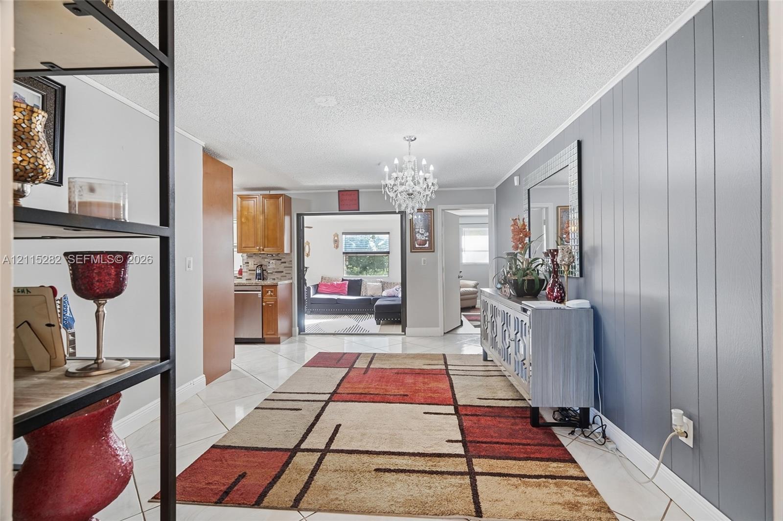 Interior featuring ceramic tile flooring, a multi-tiered crystal chandelier, and a vertical wood-paneled accent wall Interior featuring ceramic tile flooring, a multi-tiered crystal chandelier, and a vertical wood-paneled accent wall