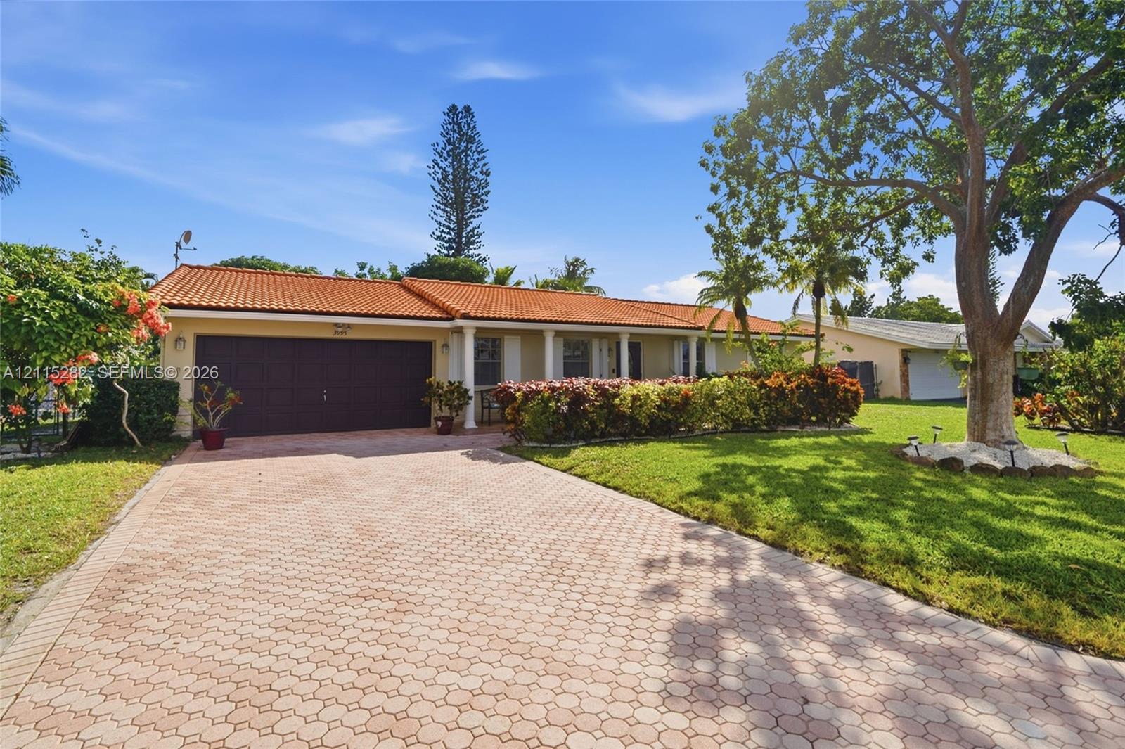 Single-story exterior featuring a clay tile roof, paver driveway, covered entryway with columns, and mature landscaping Single-story exterior featuring a clay tile roof, paver driveway, covered entryway with columns, and mature landscaping
