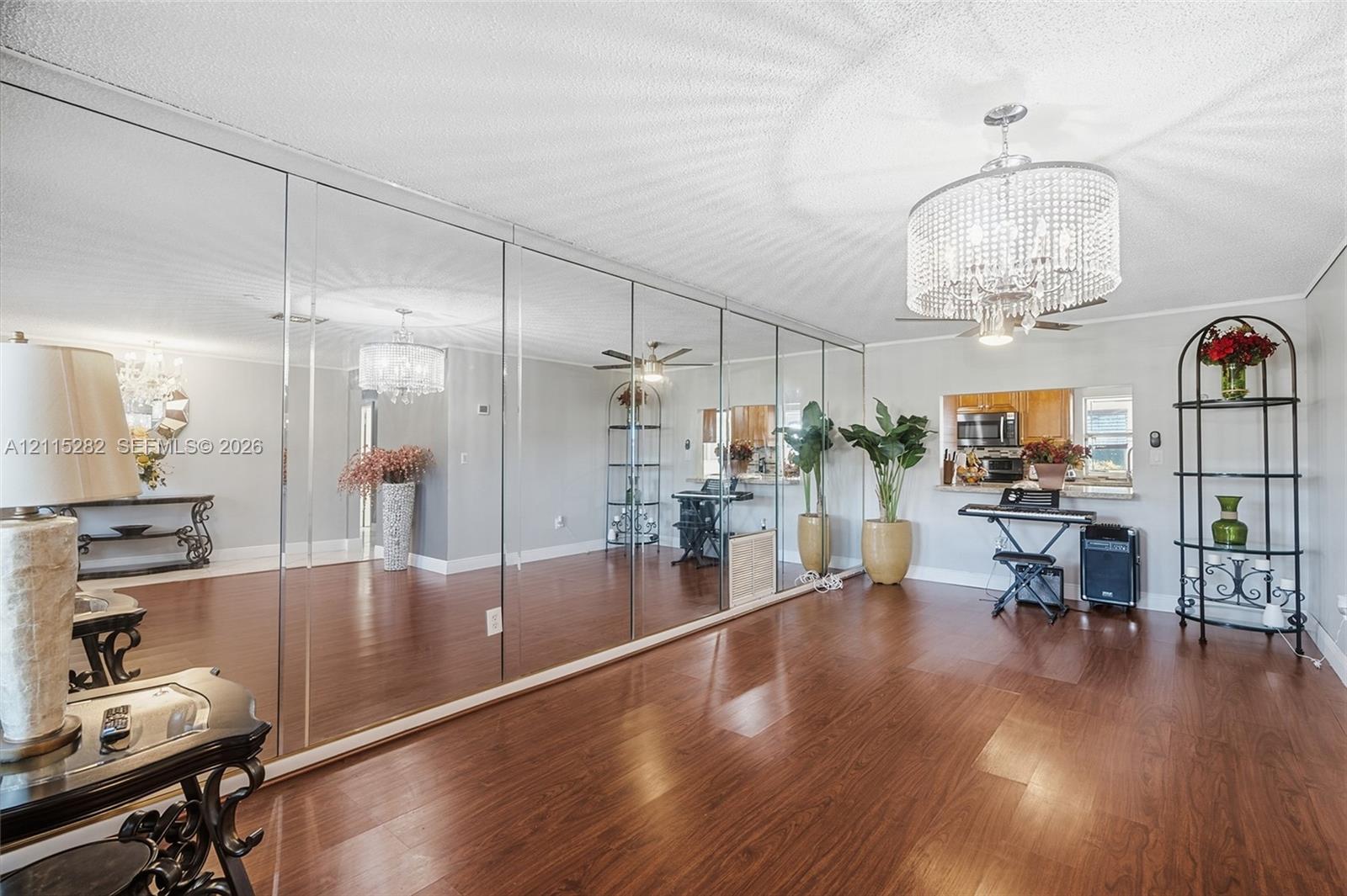 Expansive wall-to-wall mirrored paneling, wood-finish flooring, and a tiered crystal chandelier fixture Expansive wall-to-wall mirrored paneling, wood-finish flooring, and a tiered crystal chandelier fixture