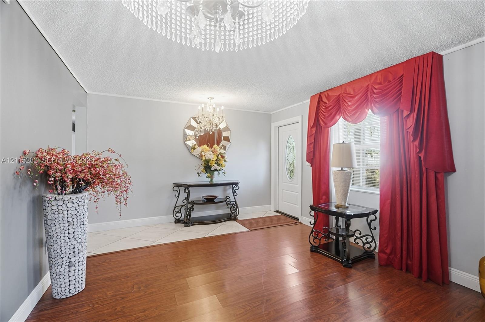 Entryway featuring wood-finish flooring, diamond-pattern tile inlay, decorative crystal chandeliers, and an exterior door with a leaded glass insert Entryway featuring wood-finish flooring, diamond-pattern tile inlay, decorative crystal chandeliers, and an exterior door with a leaded glass insert