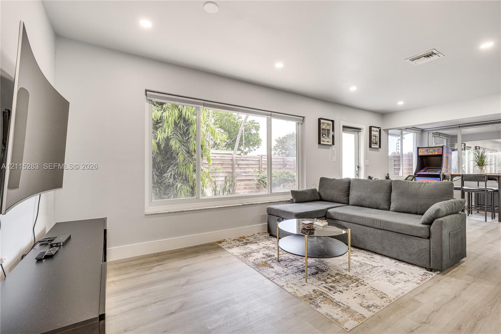 Neutral-toned interior featuring wood-finish flooring, recessed lighting, and a large picture window Neutral-toned interior featuring wood-finish flooring, recessed lighting, and a large picture window