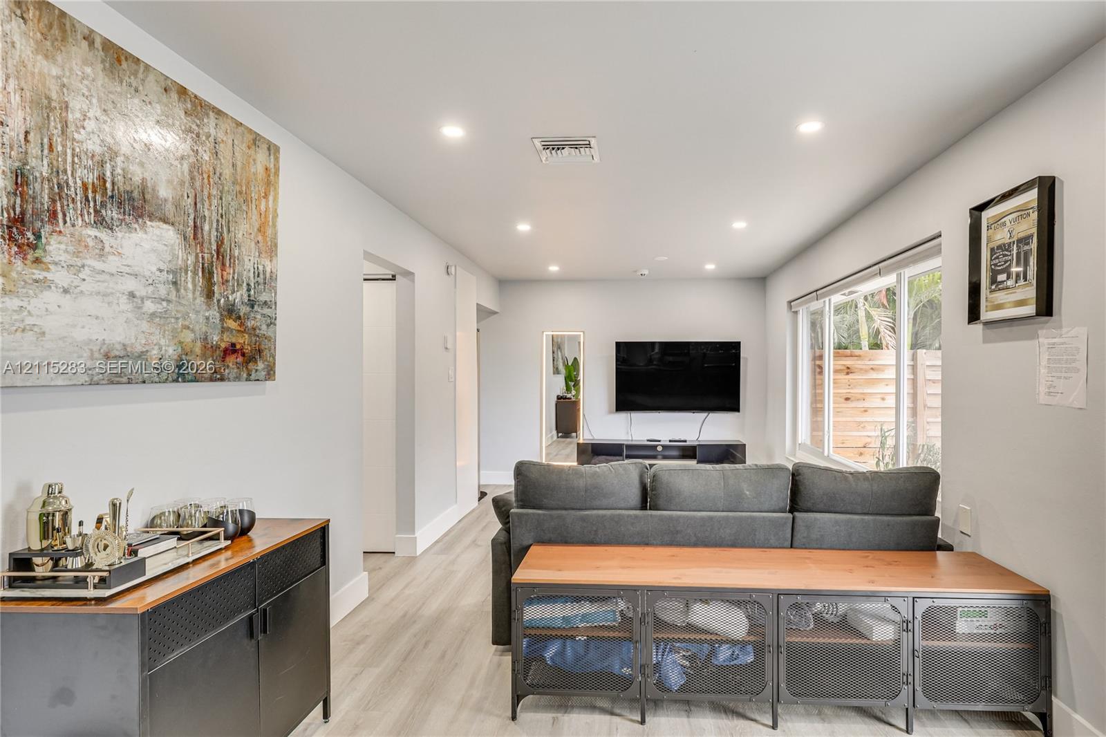 Interior space featuring light-toned wood-finish flooring, recessed lighting, and large windows with horizontal blinds Interior space featuring light-toned wood-finish flooring, recessed lighting, and large windows with horizontal blinds