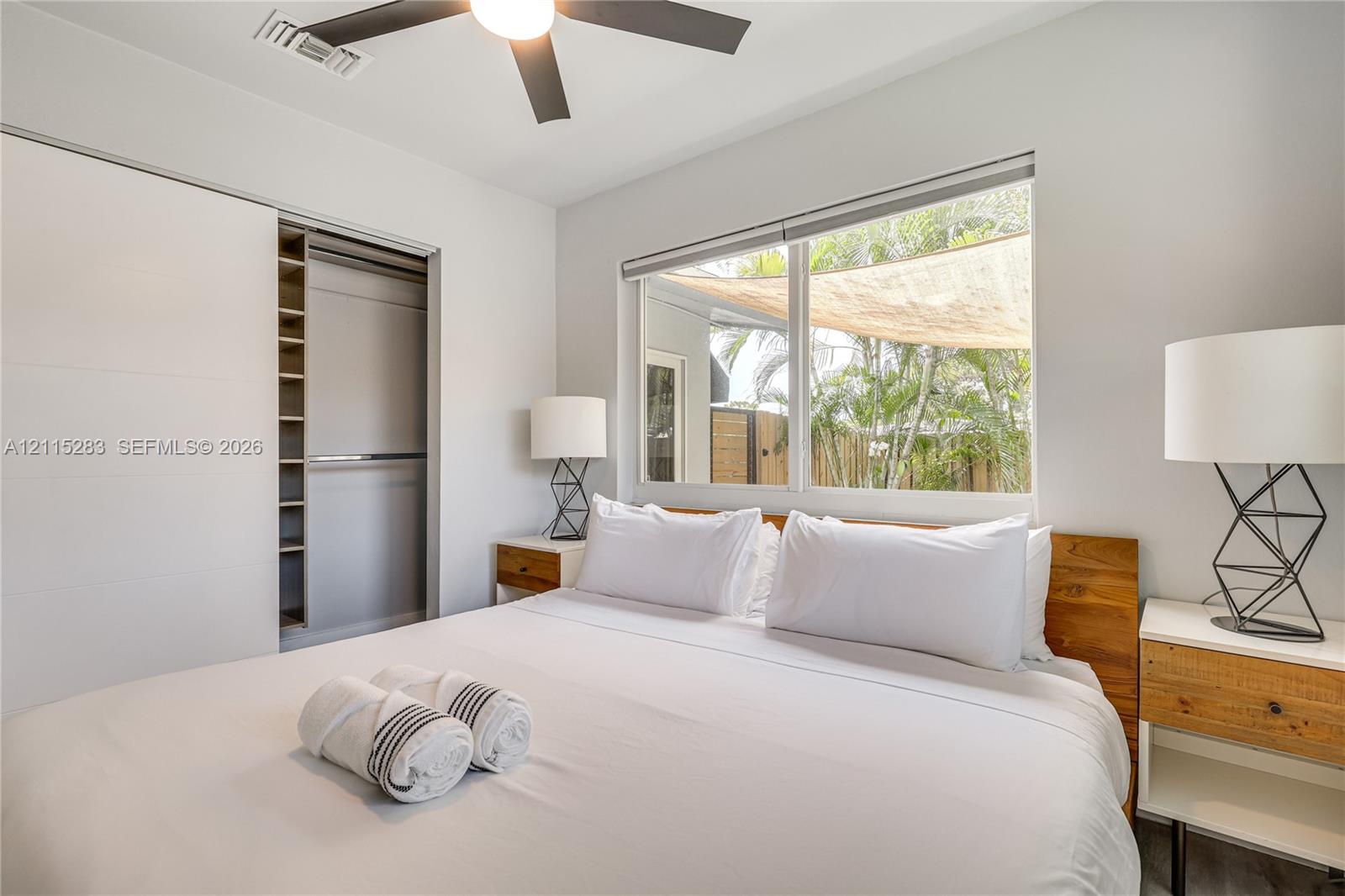 Built-in closet with shelving, large-format window, and ceiling fan