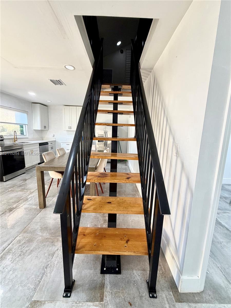 Staircase featuring natural wood-finish treads and a structural black metal frame with matching vertical railing