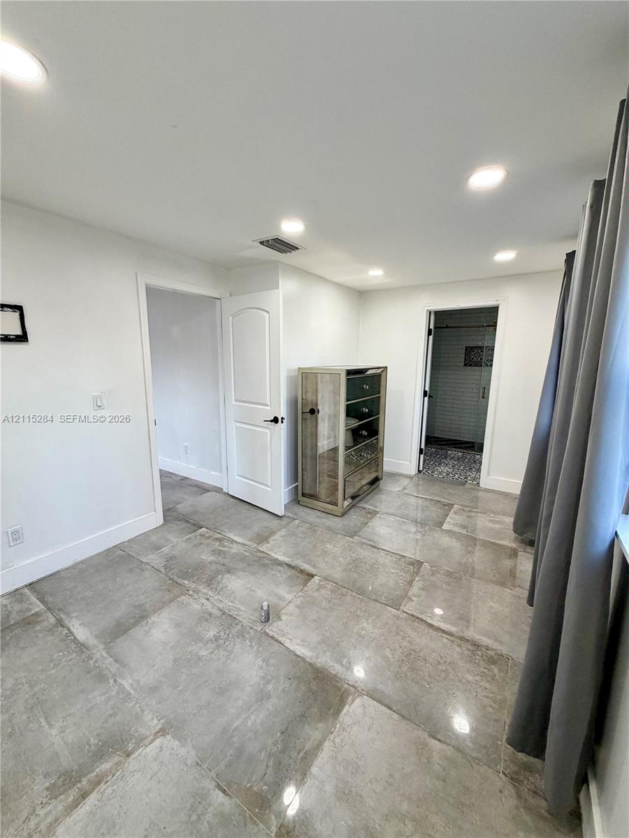 Large-format stone-style tile flooring, recessed ceiling lighting, and solid-core interior doors