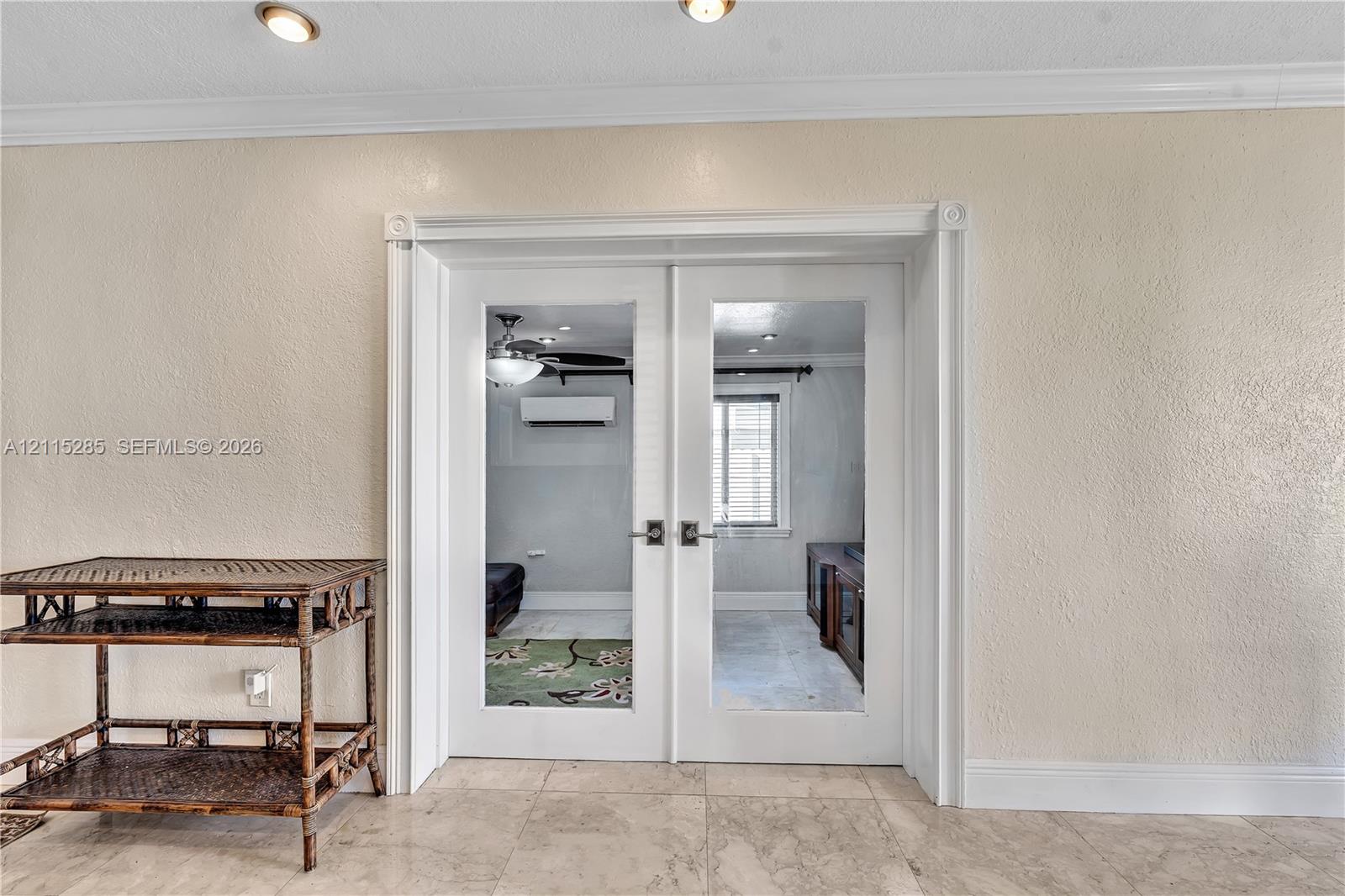 White French doors with glass panels, crown molding, stone-finish flooring, and recessed ceiling lighting