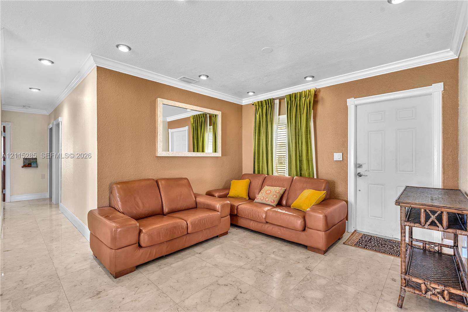 Interior space featuring polished stone-finish tile flooring, recessed ceiling lighting, crown molding, and a wall-mounted mirror with a light-tone frame