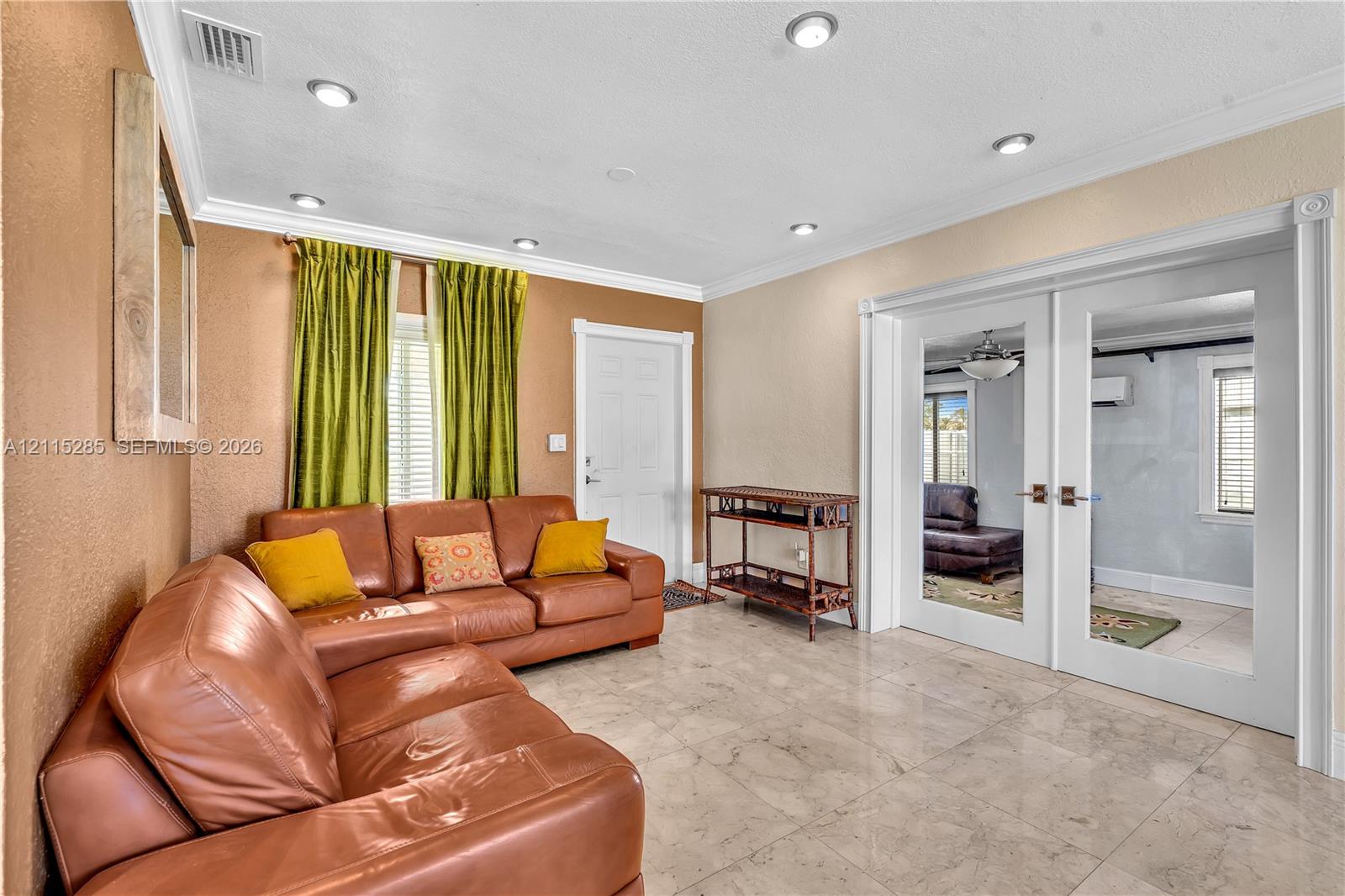 Polished stone tile flooring, recessed lighting, crown molding, and white-framed French doors with glass panels