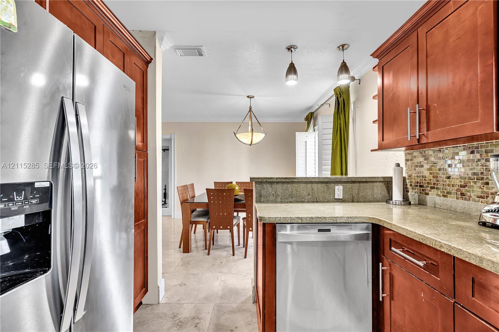 Kitchen featuring wood cabinetry, stone countertops, a mosaic tile backsplash, stainless steel appliances, and tile flooring