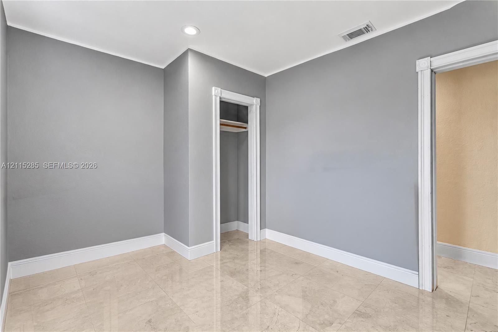 Neutral-toned interior featuring stone-finish tile flooring, recessed ceiling lighting, and a closet with built-in shelving