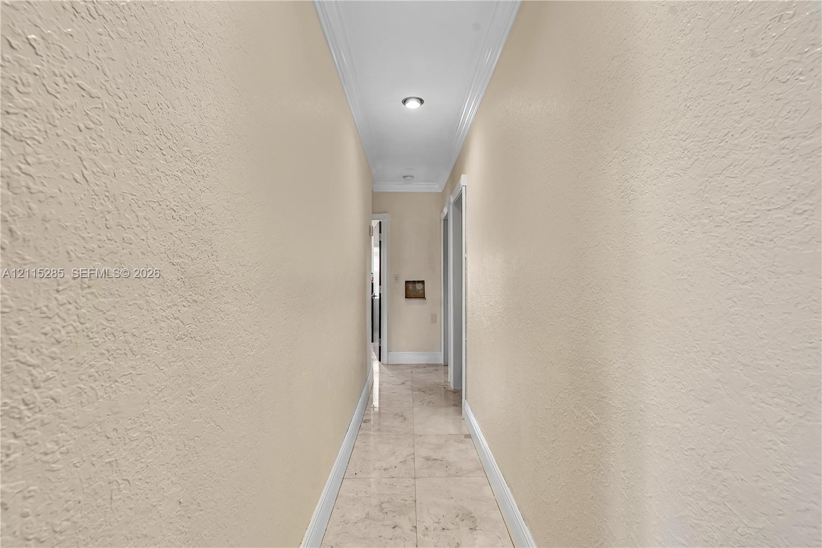 Hallway featuring neutral-toned wall paint, crown molding, recessed ceiling lighting, and tile flooring