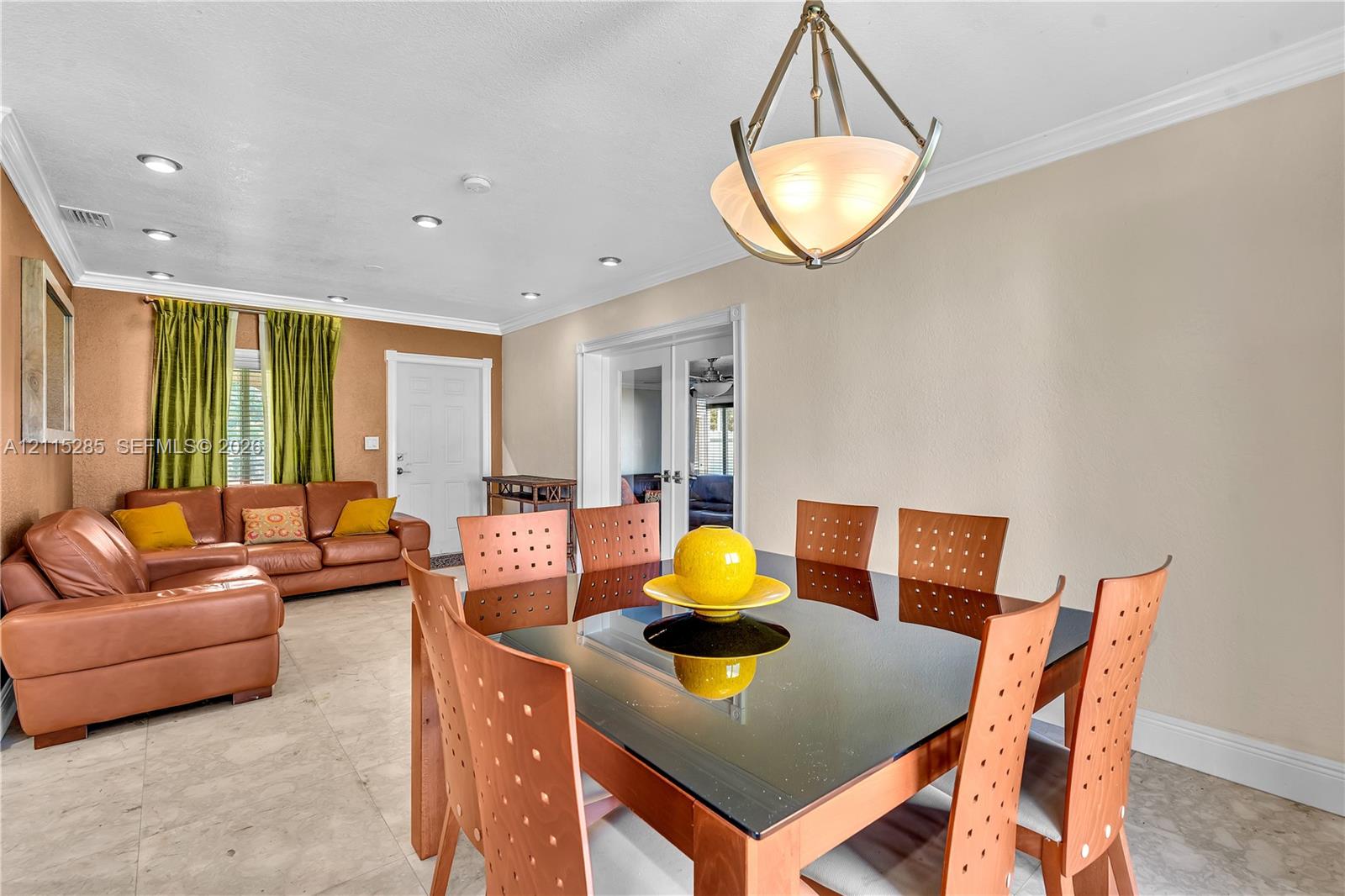 Neutral-toned tile flooring, recessed lighting, crown molding, and a geometric-style metal pendant light fixture