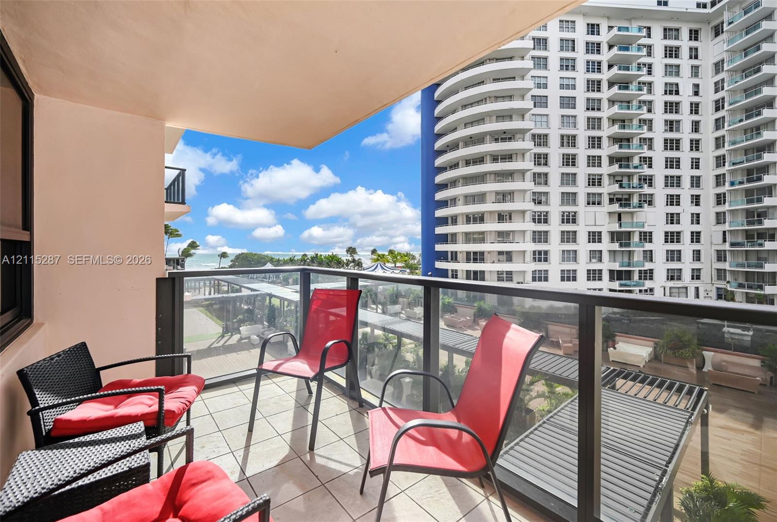 Covered balcony featuring tile flooring and a glass-paneled railing