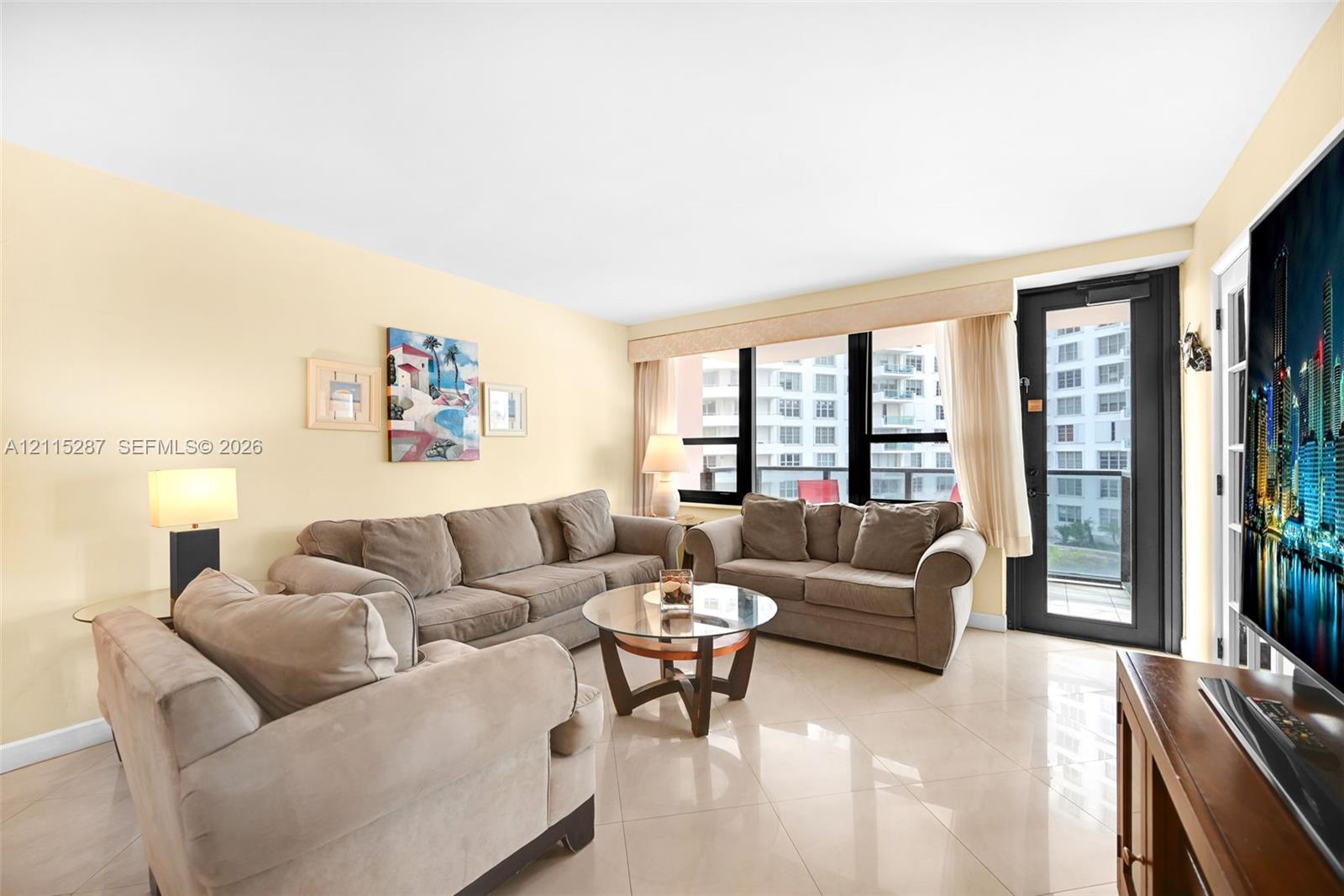 Living area featuring polished tile flooring, floor-to-ceiling windows, and a glass-paned door providing exterior access