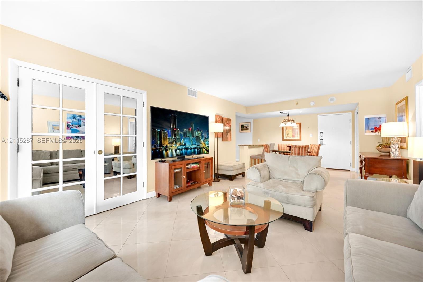 Open-concept interior featuring light-toned tile flooring, French doors with glass panes, and a breakfast bar
