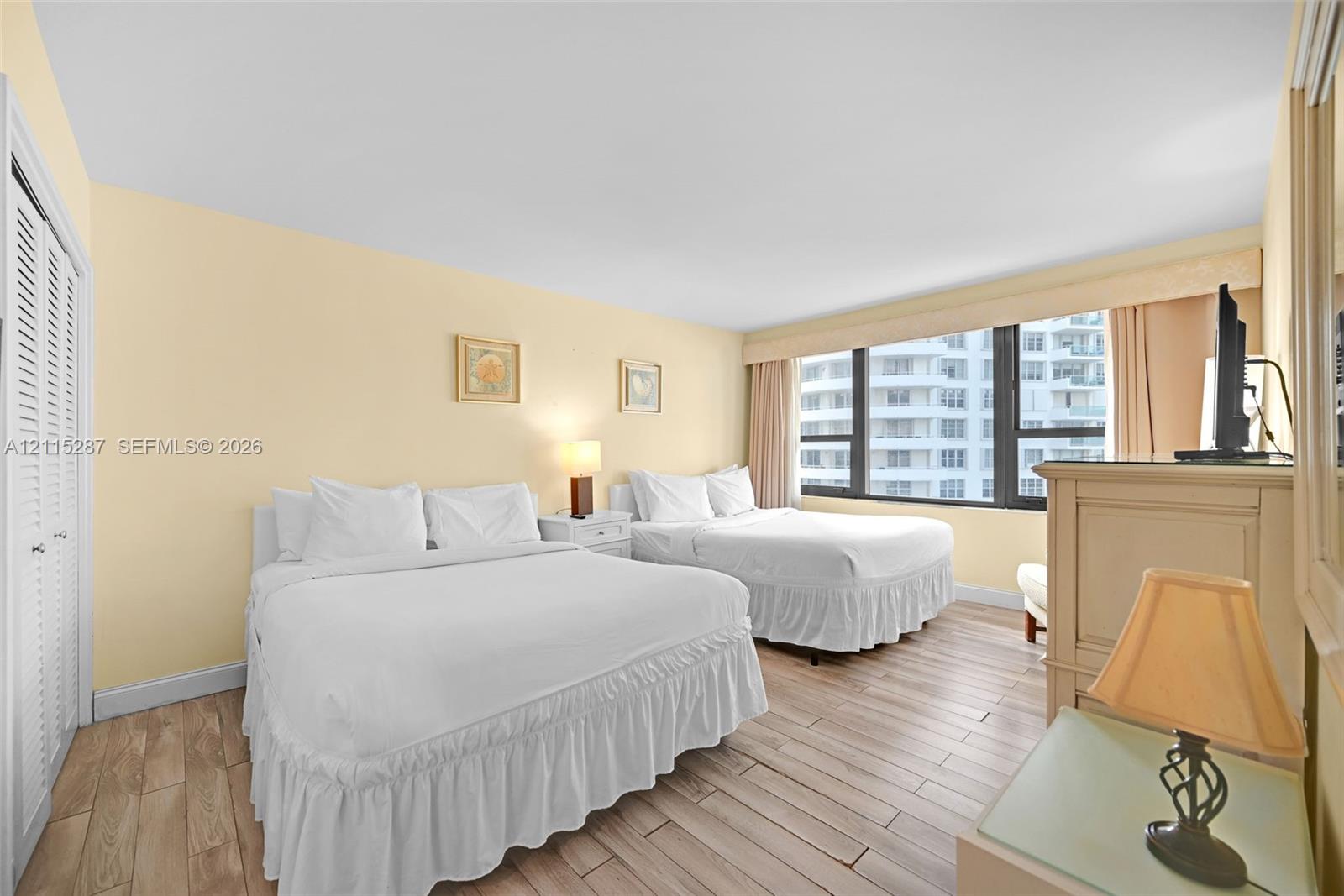 Large floor-to-ceiling windows, wood-finish flooring, and white louvered closet doors