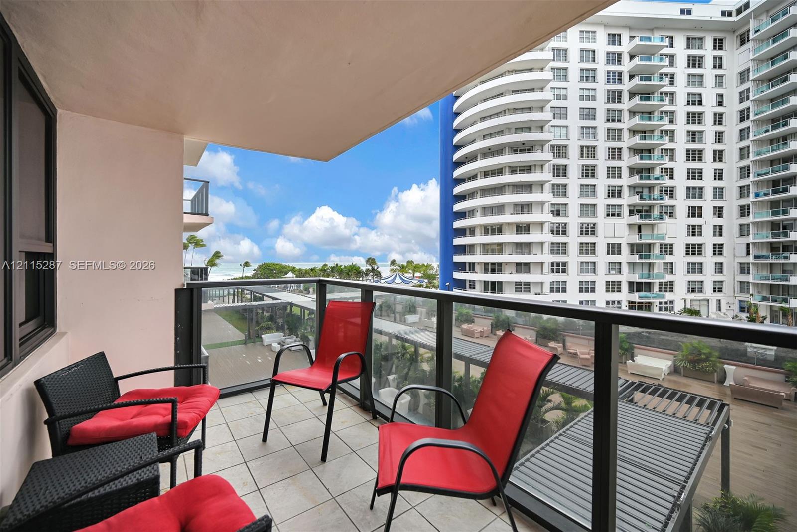 Covered balcony featuring tile flooring and a glass-paneled railing