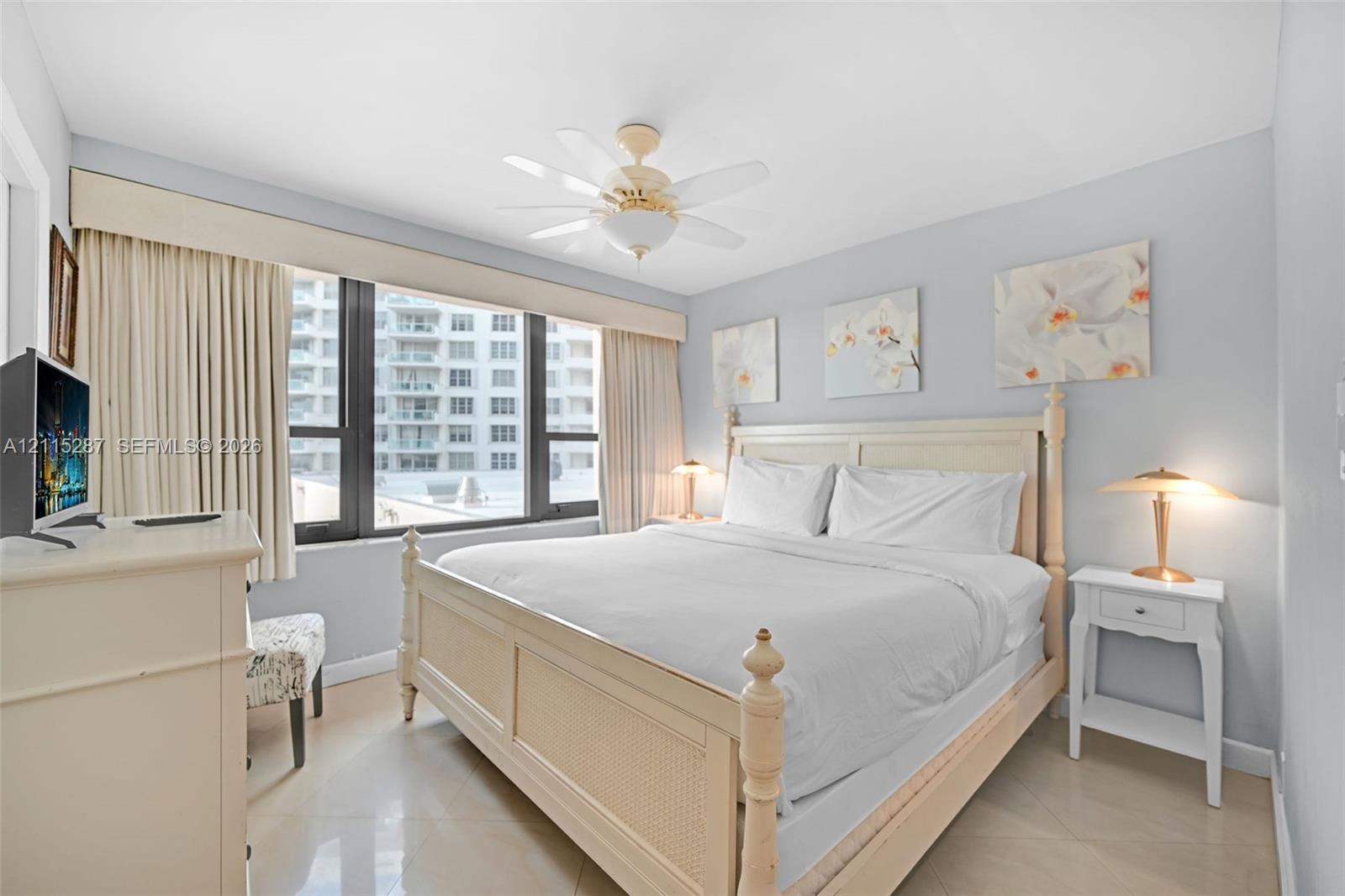 Large floor-to-ceiling windows with custom cornice detailing, light-toned tiled flooring, and a ceiling-mounted fan fixture