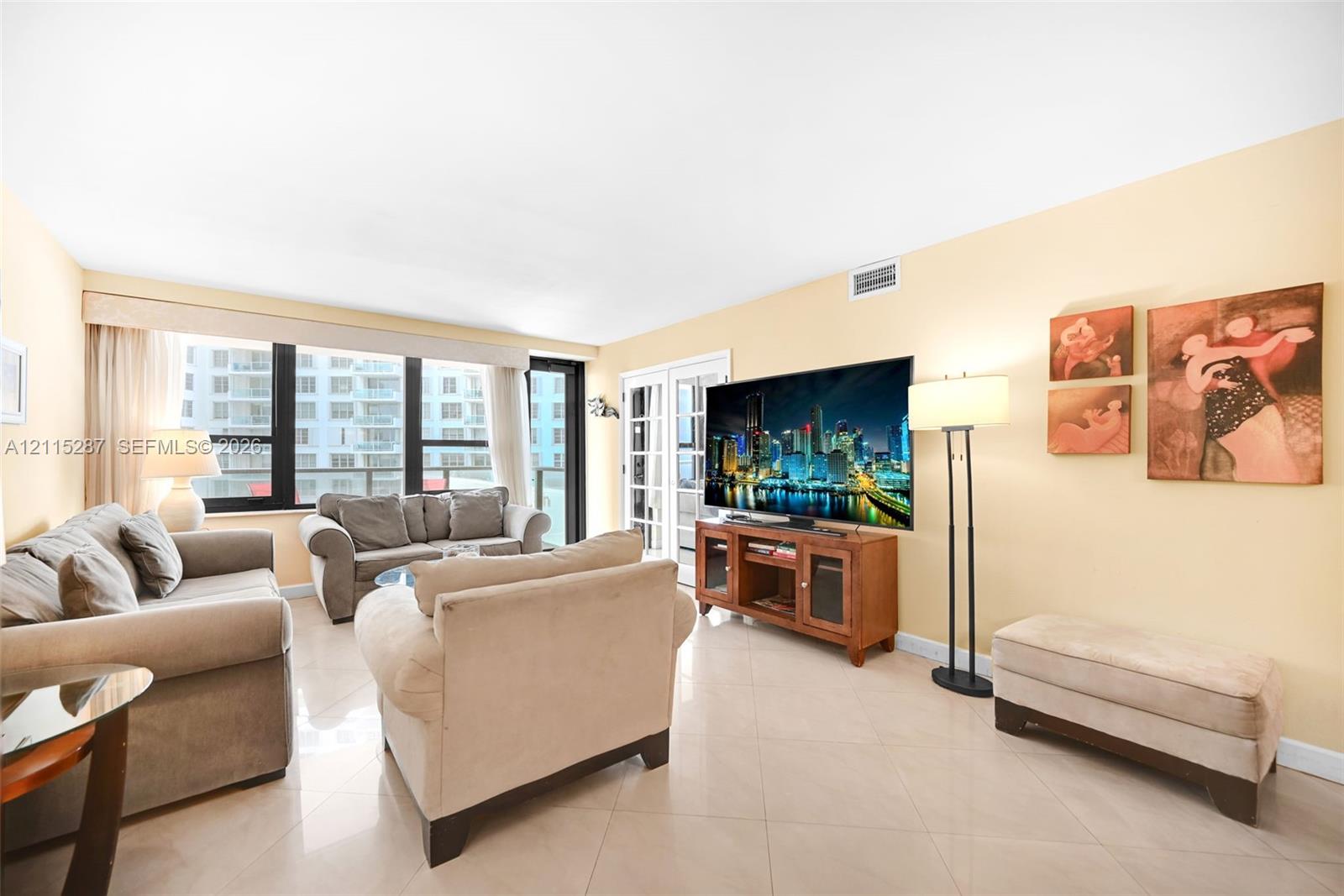 Living area featuring large-format ceramic tile flooring, floor-to-ceiling windows, and glass-paneled patio doors
