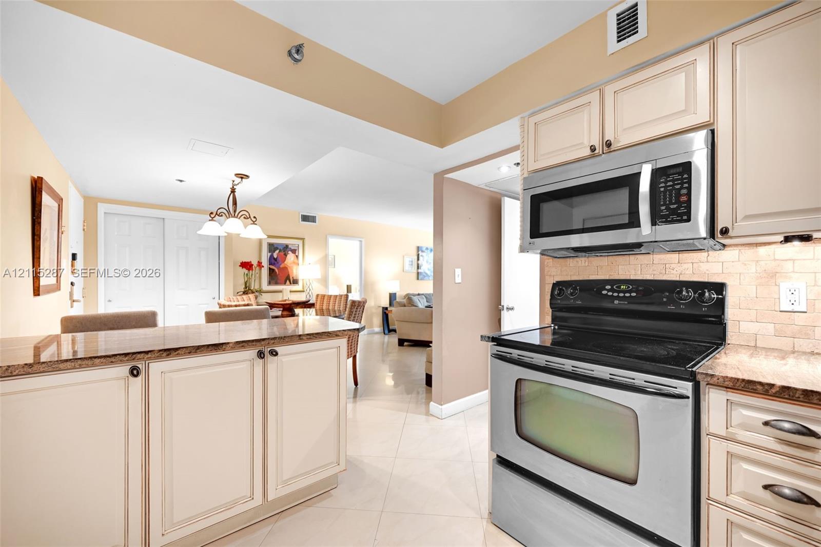 Kitchen featuring stainless steel appliances, neutral cabinetry, stone-finish countertops, tiled backsplash, and ceramic floor tiling