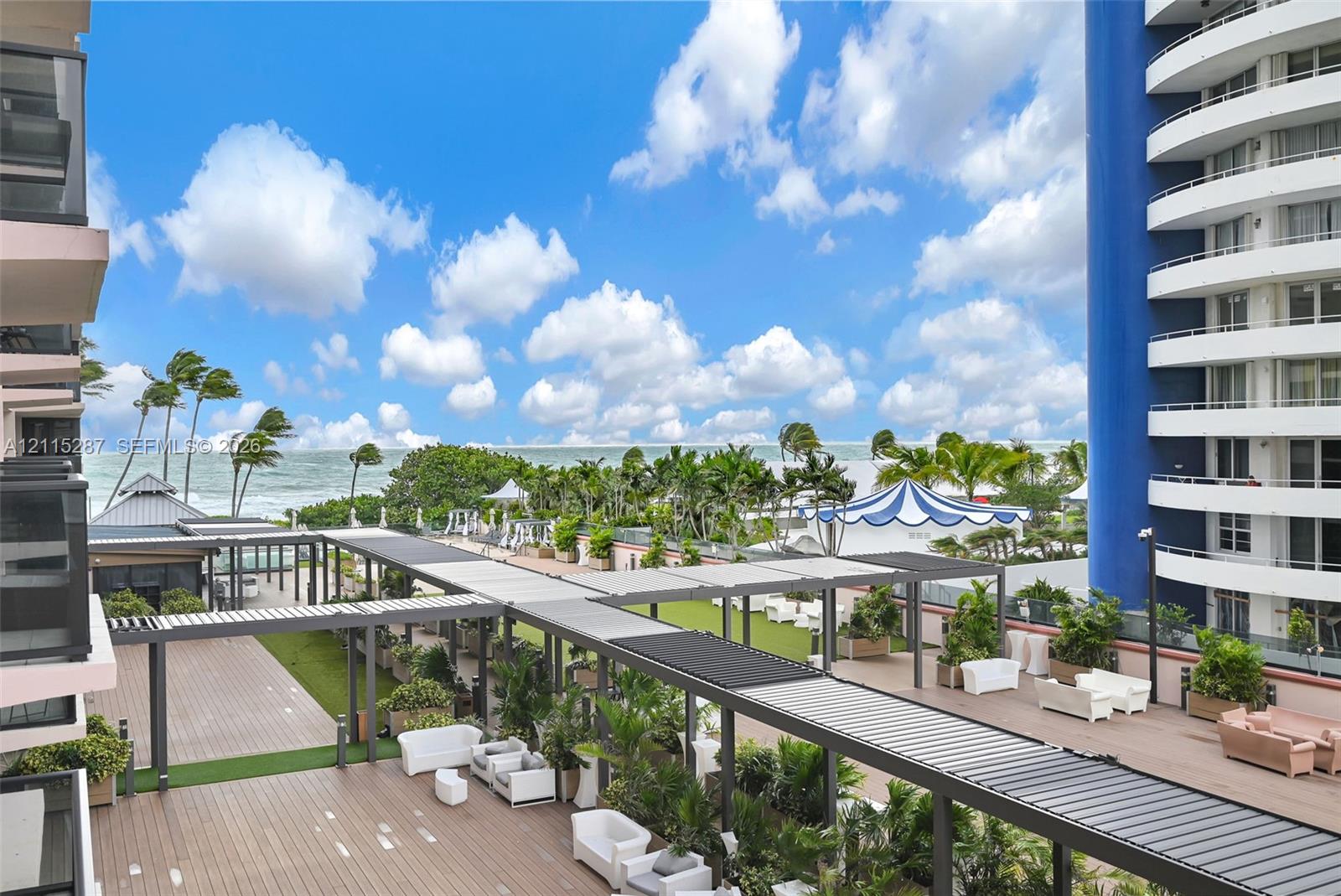 Expansive elevated terrace featuring wood-finish decking, integrated metal pergola structures, built-in landscape planters, and oceanfront exposure