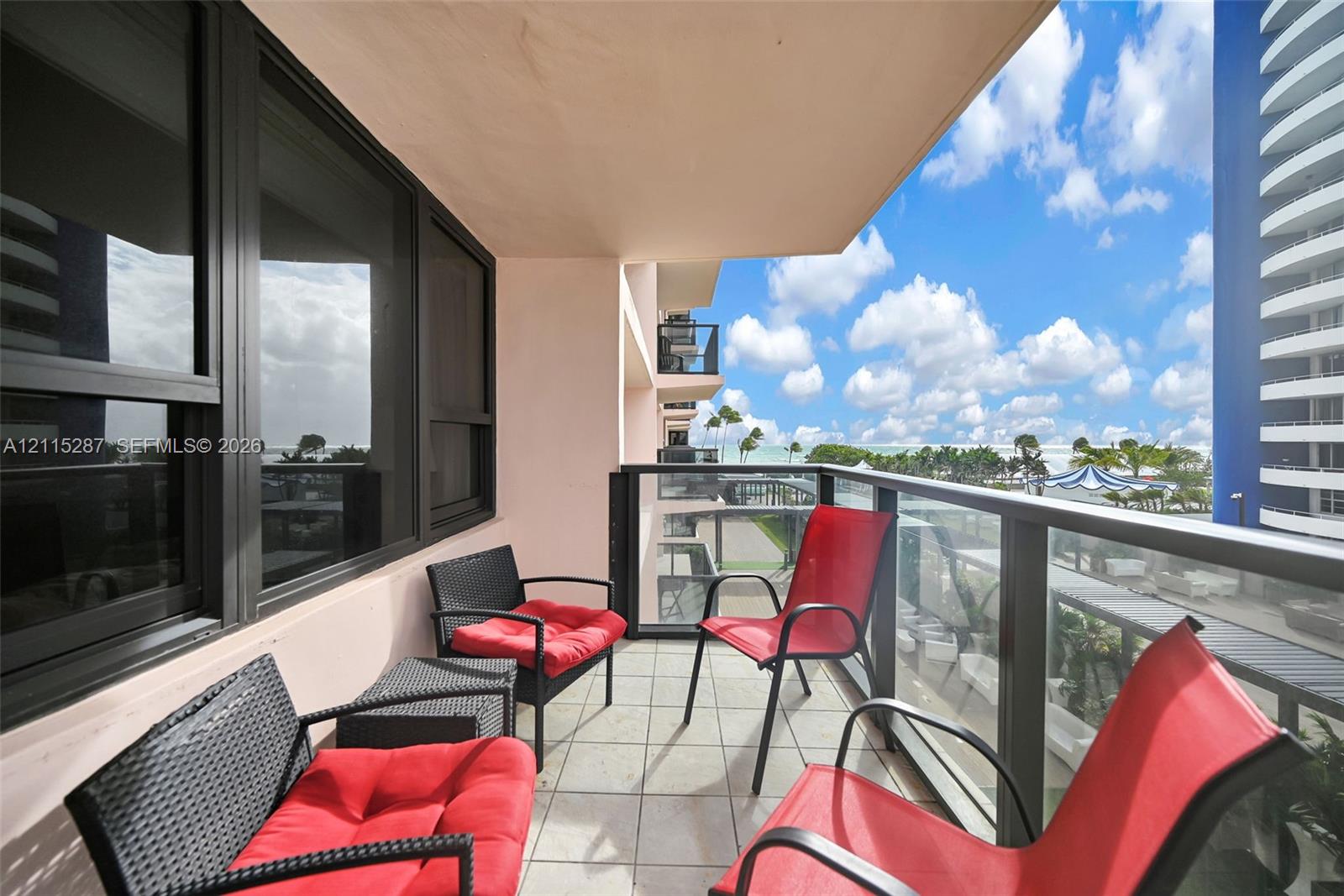 Covered balcony featuring tile flooring and a glass-paneled railing