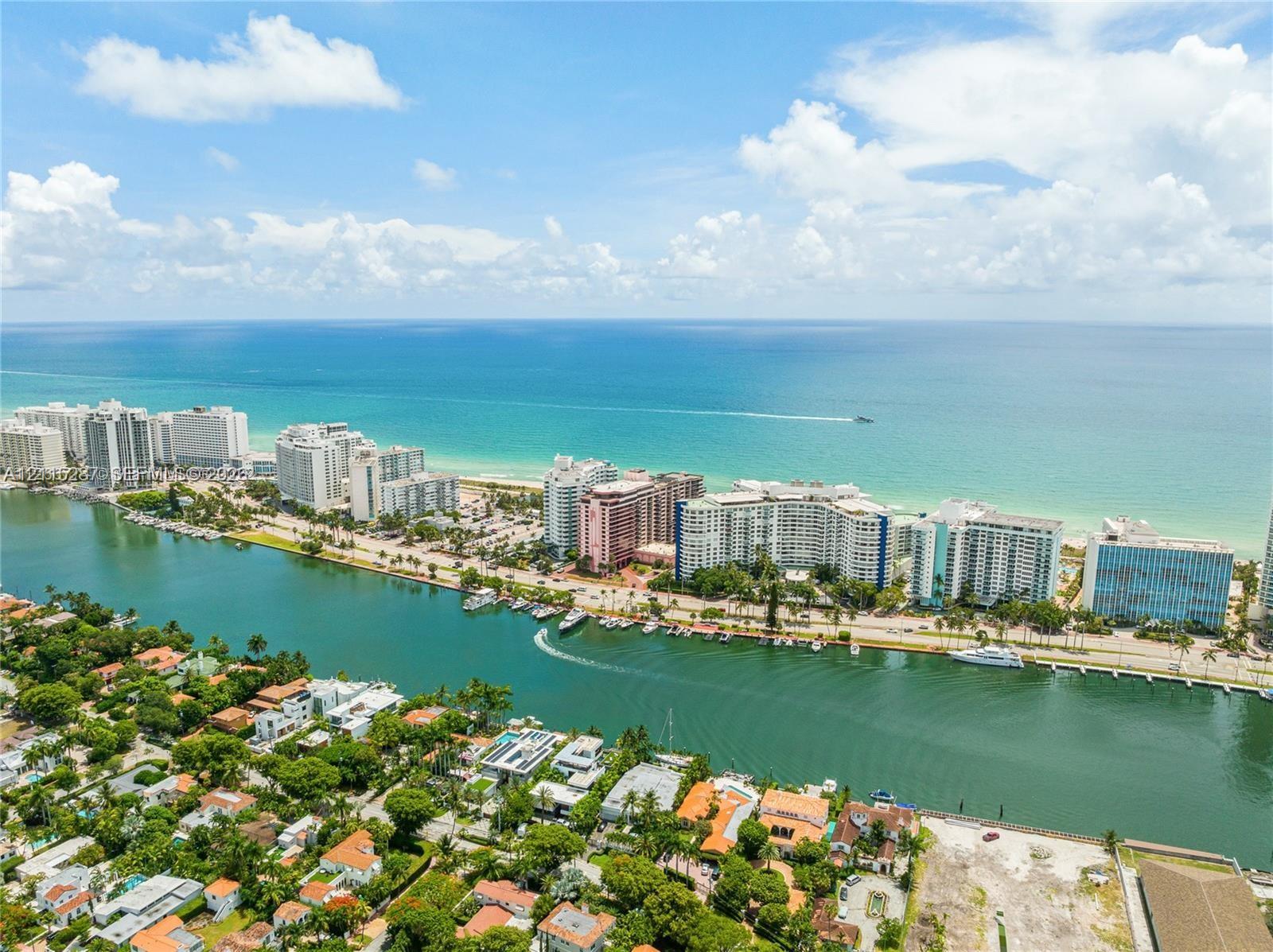 Aerial perspective of a coastal residential area featuring a deep-water canal, proximity to the Atlantic Ocean, mature tropical landscaping, and regional shoreline access