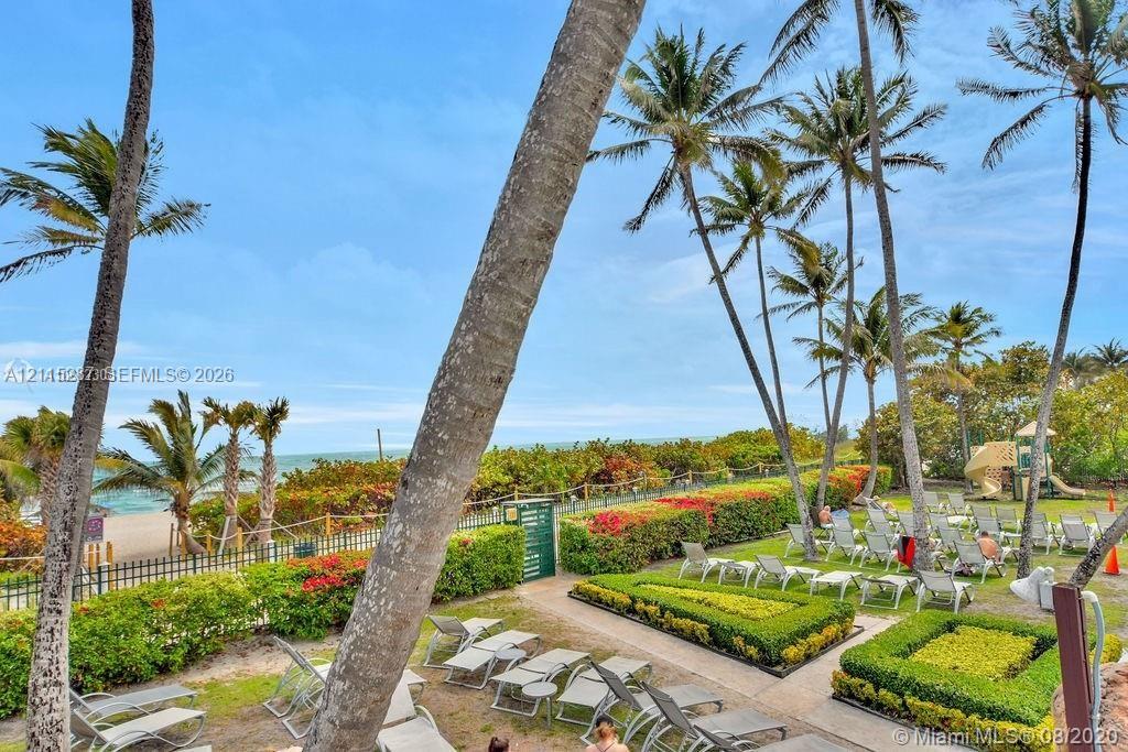 Expansive waterfront grounds featuring mature palm trees, manicured hedges, landscaped garden beds, and direct coastal access