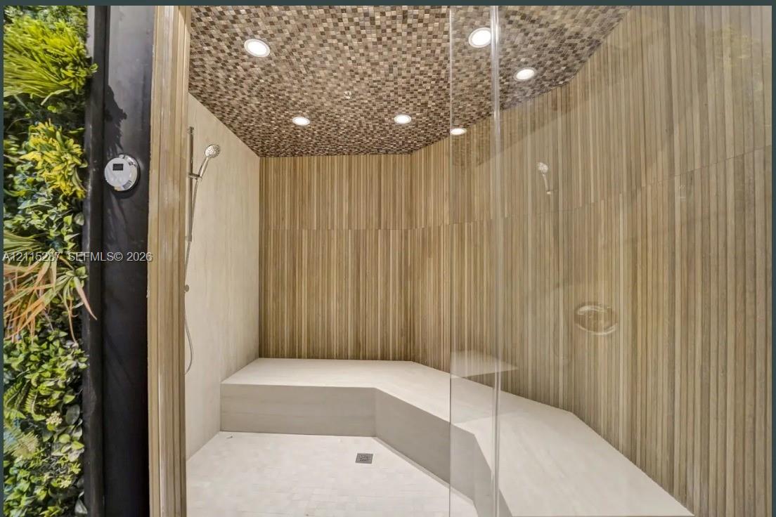 Walk-in steam shower featuring floor-to-ceiling linear tile wall cladding, mosaic tile ceiling, built-in stone bench, glass enclosure, and a vertical plant wall