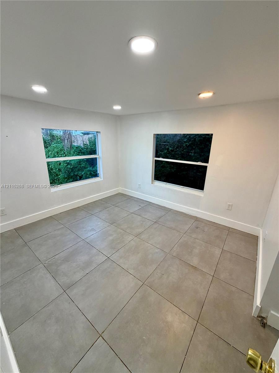 Interior space featuring neutral wall tones, large-format tile flooring, recessed ceiling lighting, and dual windows