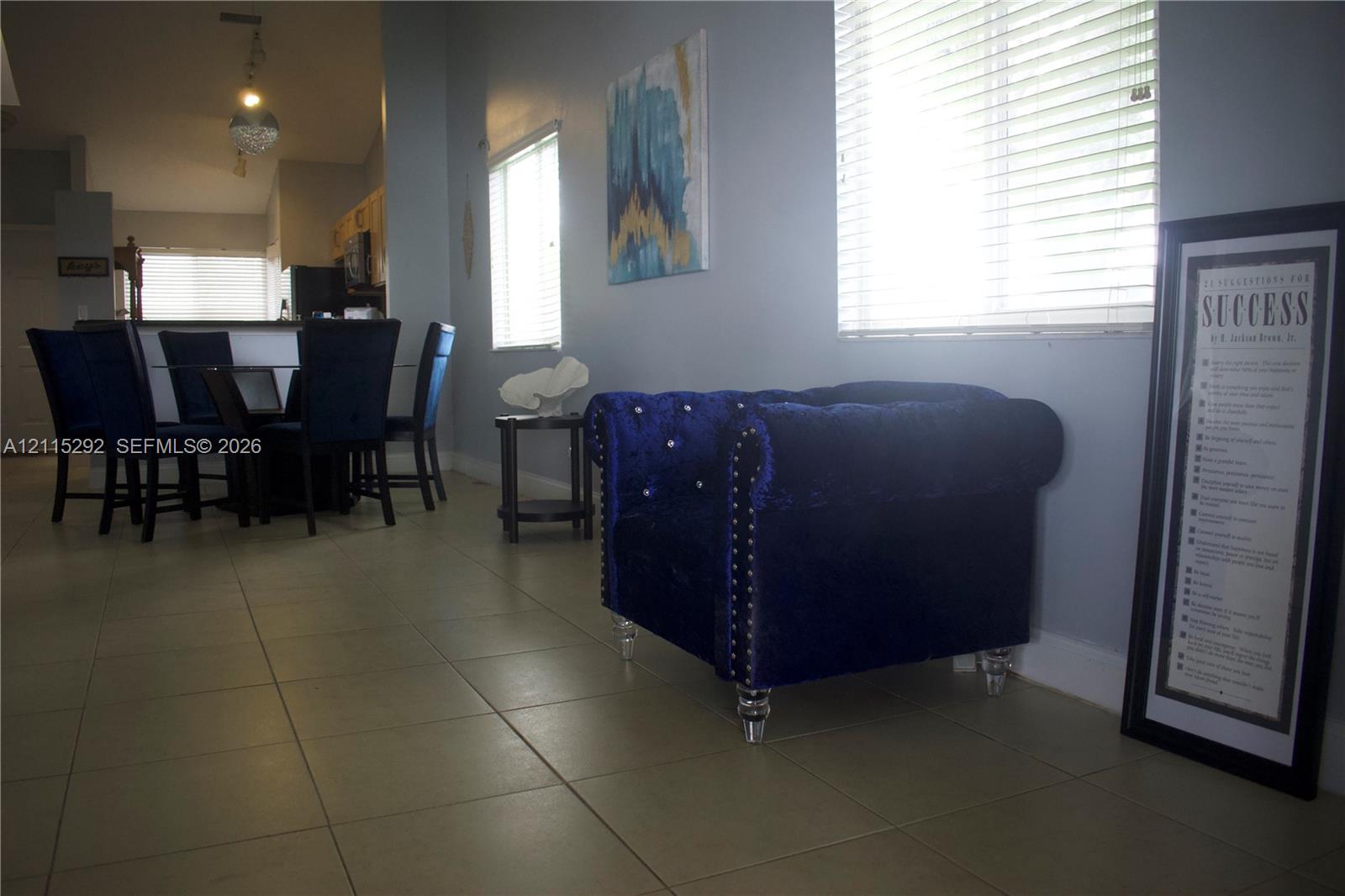 Interior space featuring large-format floor tile, vaulted ceilings, and horizontal window blinds