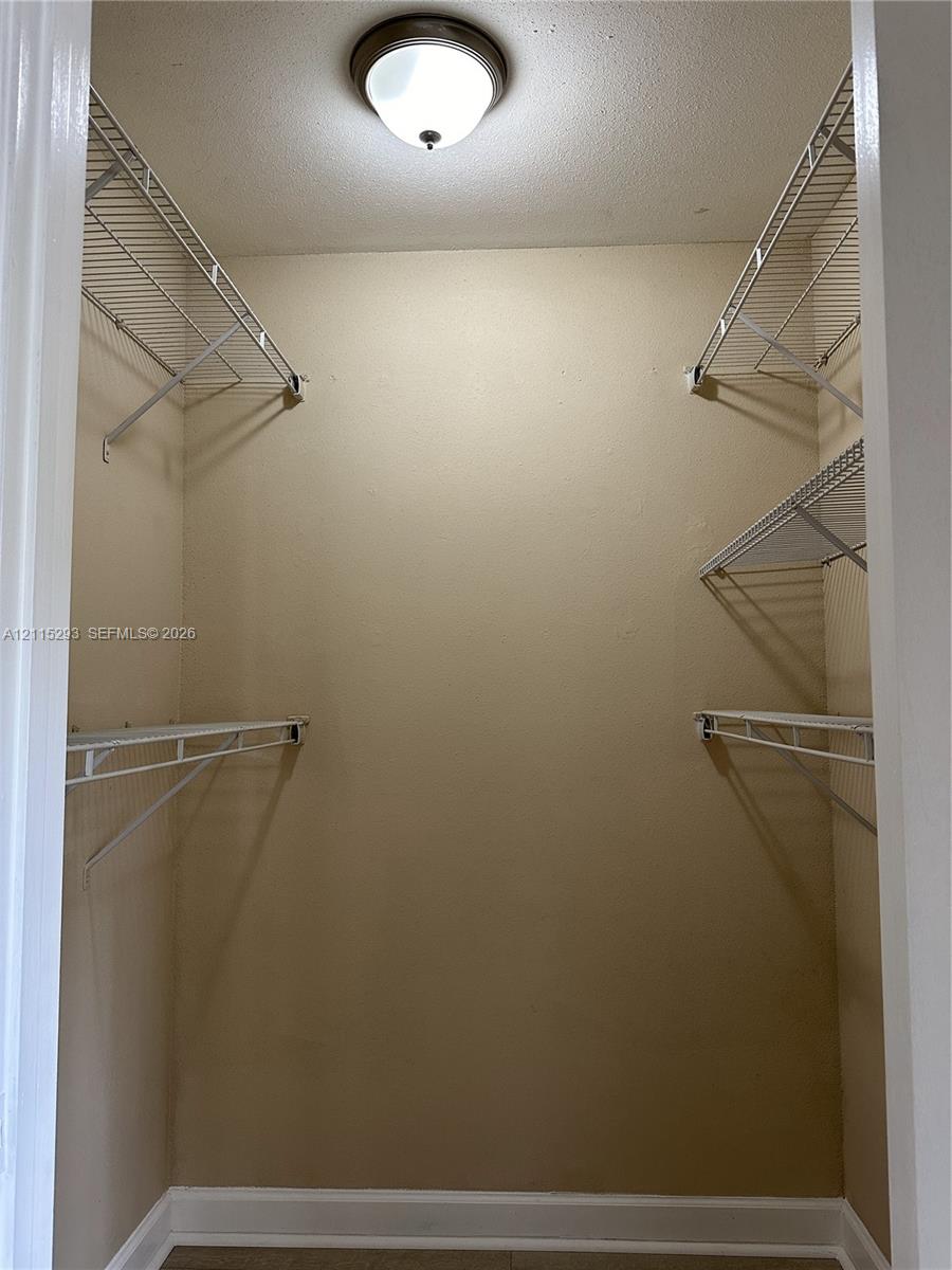 Storage space featuring white wire shelving units and a circular dome-style ceiling light fixture