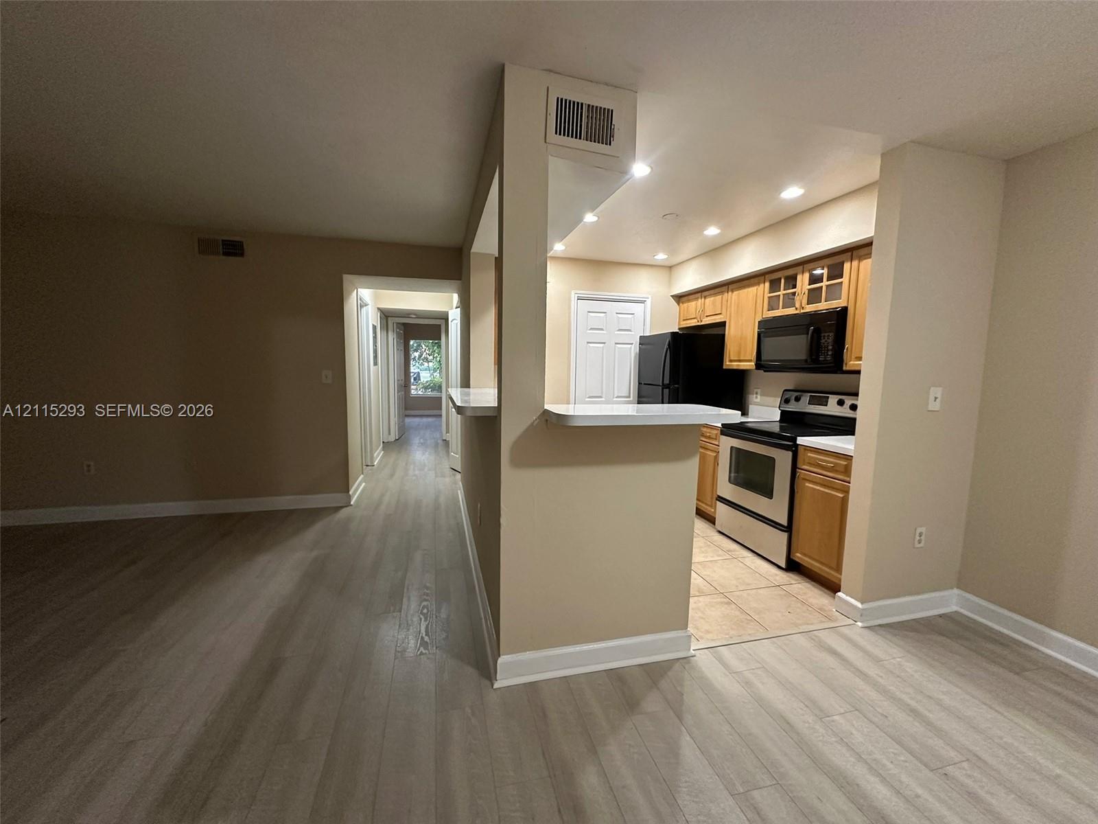 Kitchen featuring wood-finish cabinetry, a breakfast bar, recessed lighting, and tile flooring