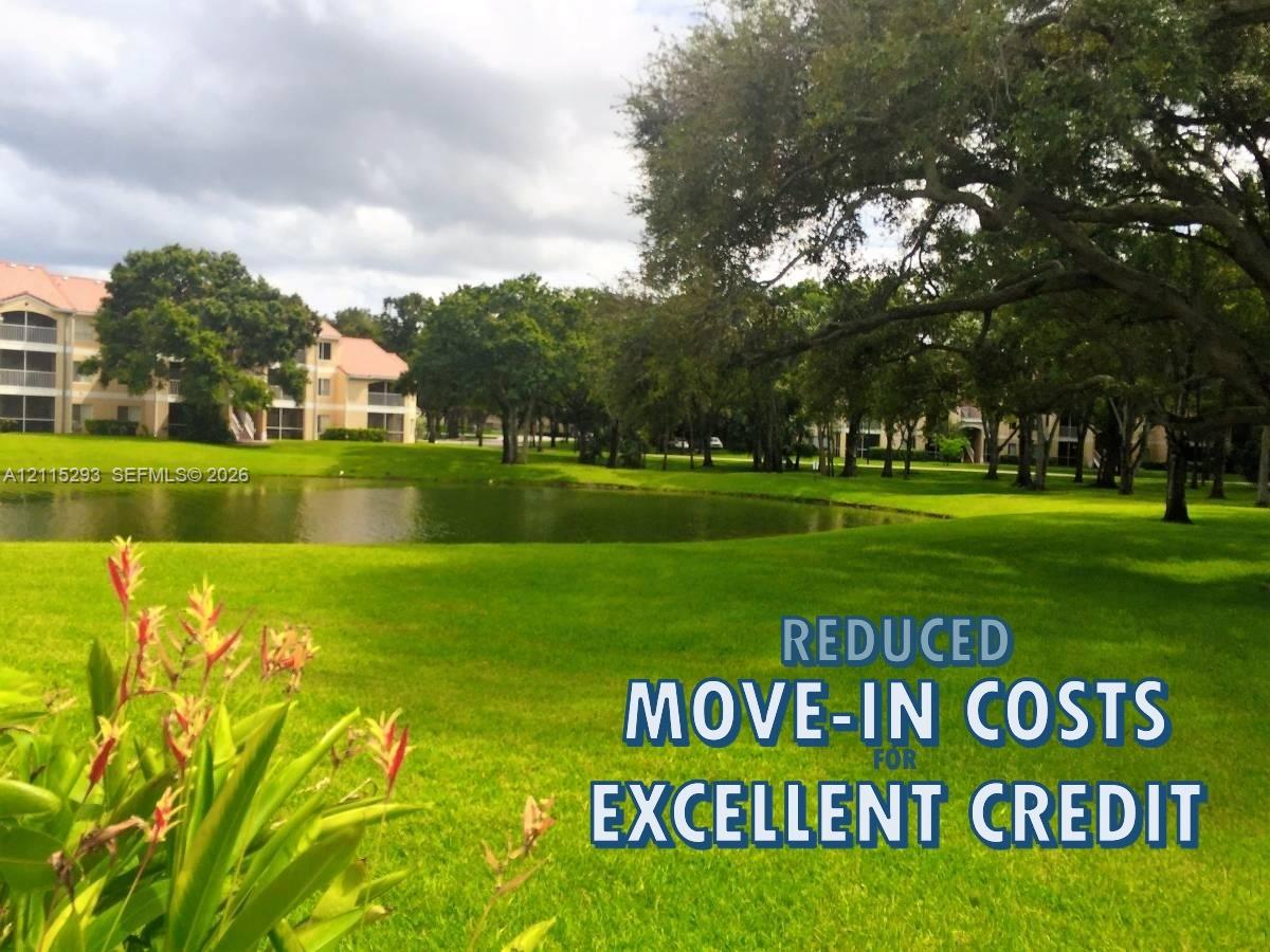 Expansive manicured grounds featuring a natural pond, mature shade trees, and tiered residential architecture