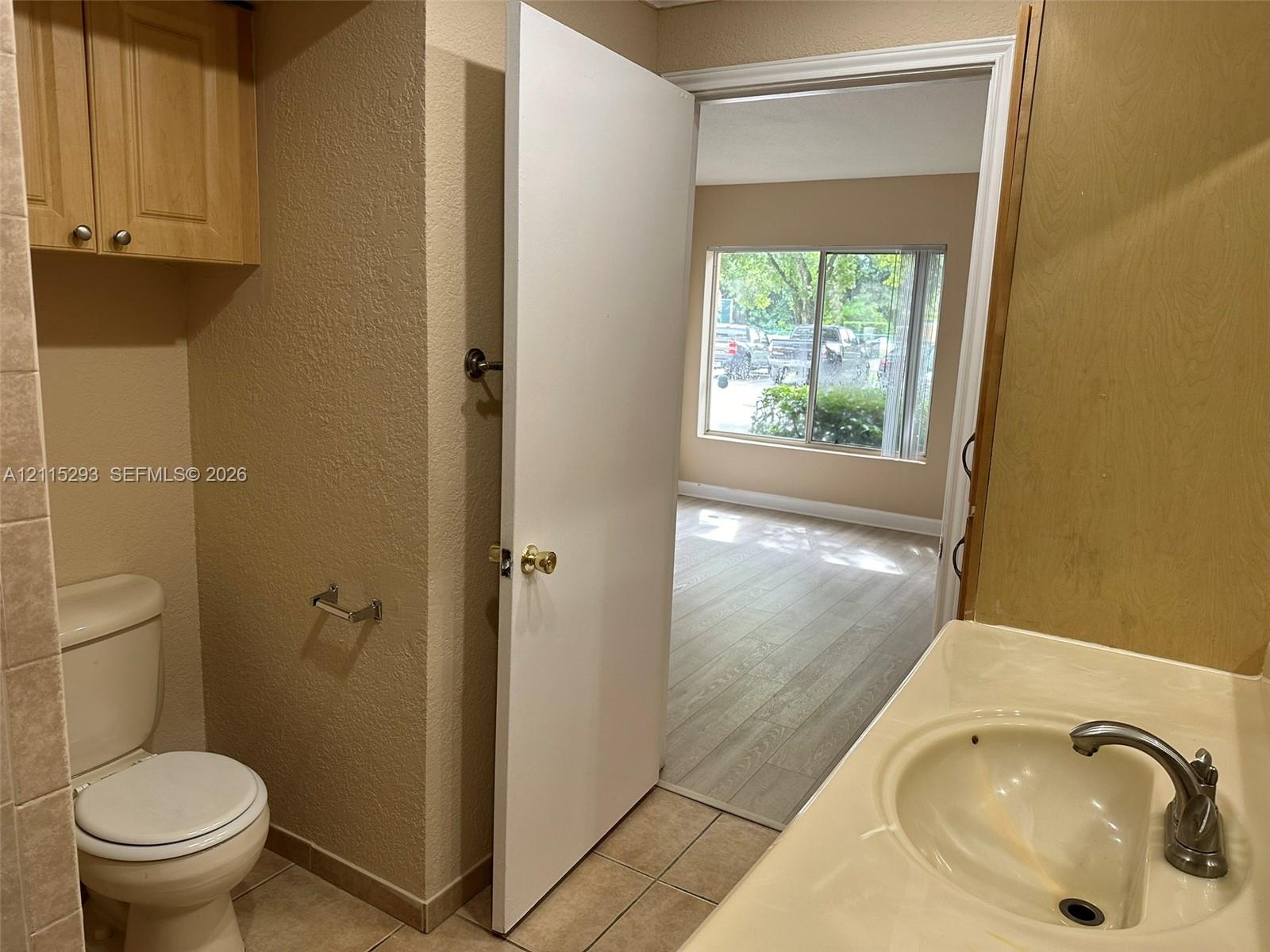 Bathroom featuring tile flooring, a built-in vanity cabinet, a molded countertop with an integrated sink, and an overhead storage cabinet
