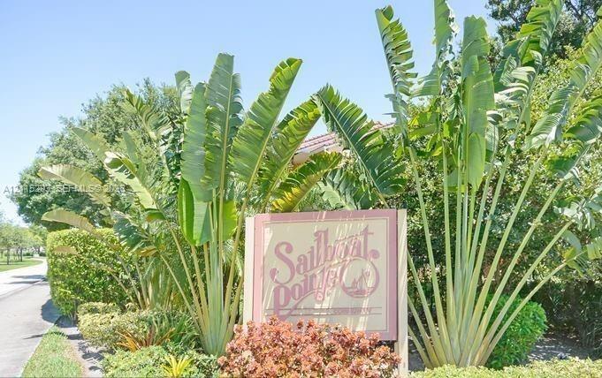 Property entrance featuring mature ornamental landscaping, established tropical vegetation, and a paved walkway