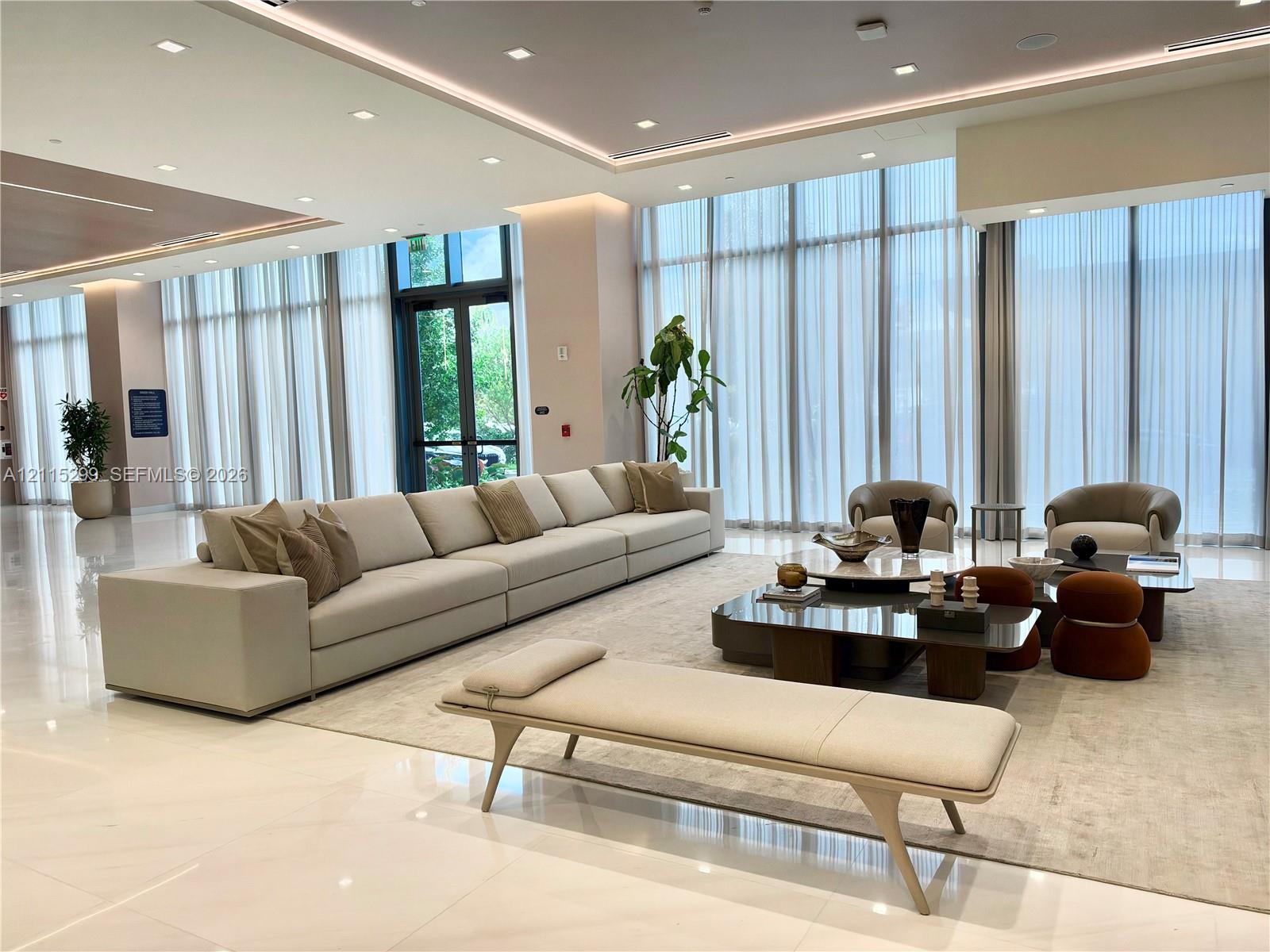 Expansive common area featuring floor-to-ceiling windows, polished large-format tile flooring, and integrated recessed lighting with cove illumination