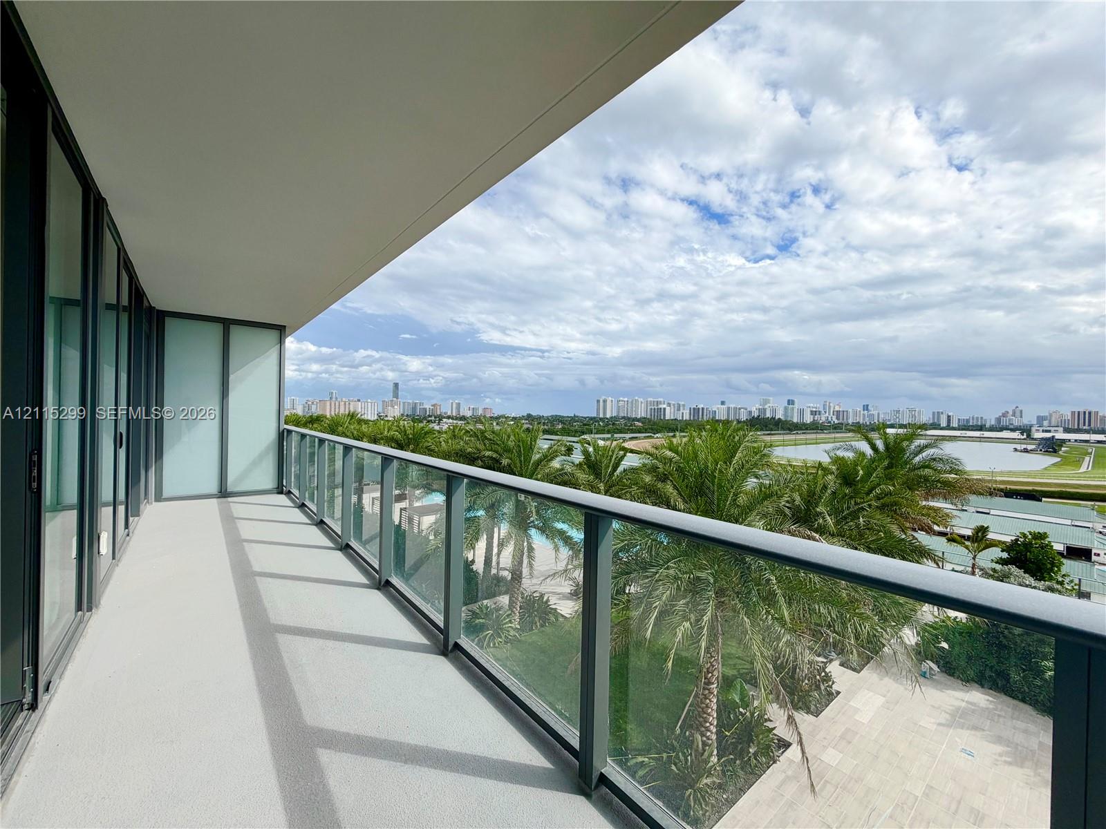 Private balcony featuring full-height glass railings, concrete flooring, and an expansive skyline and water orientation