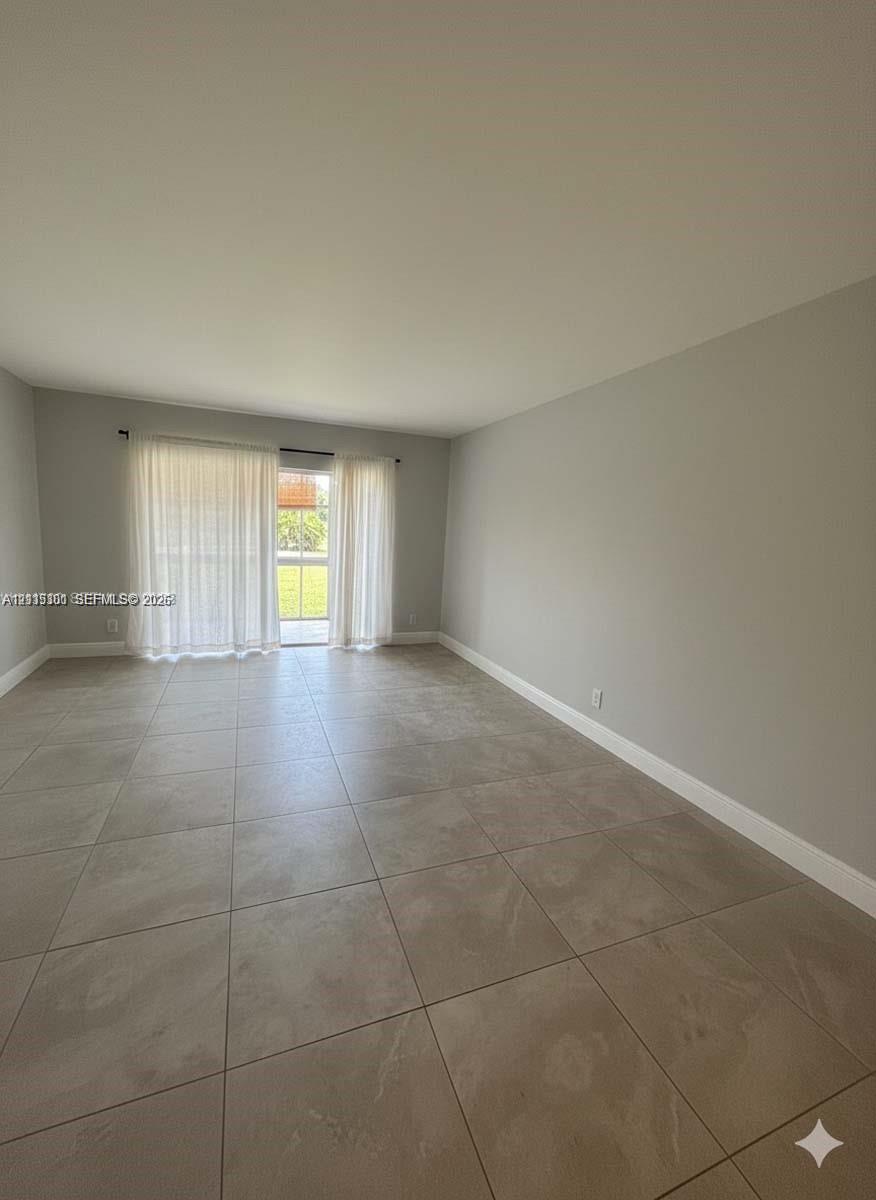 Neutral interior featuring large-format ceramic tile flooring, neutral wall paint, and sliding glass doors