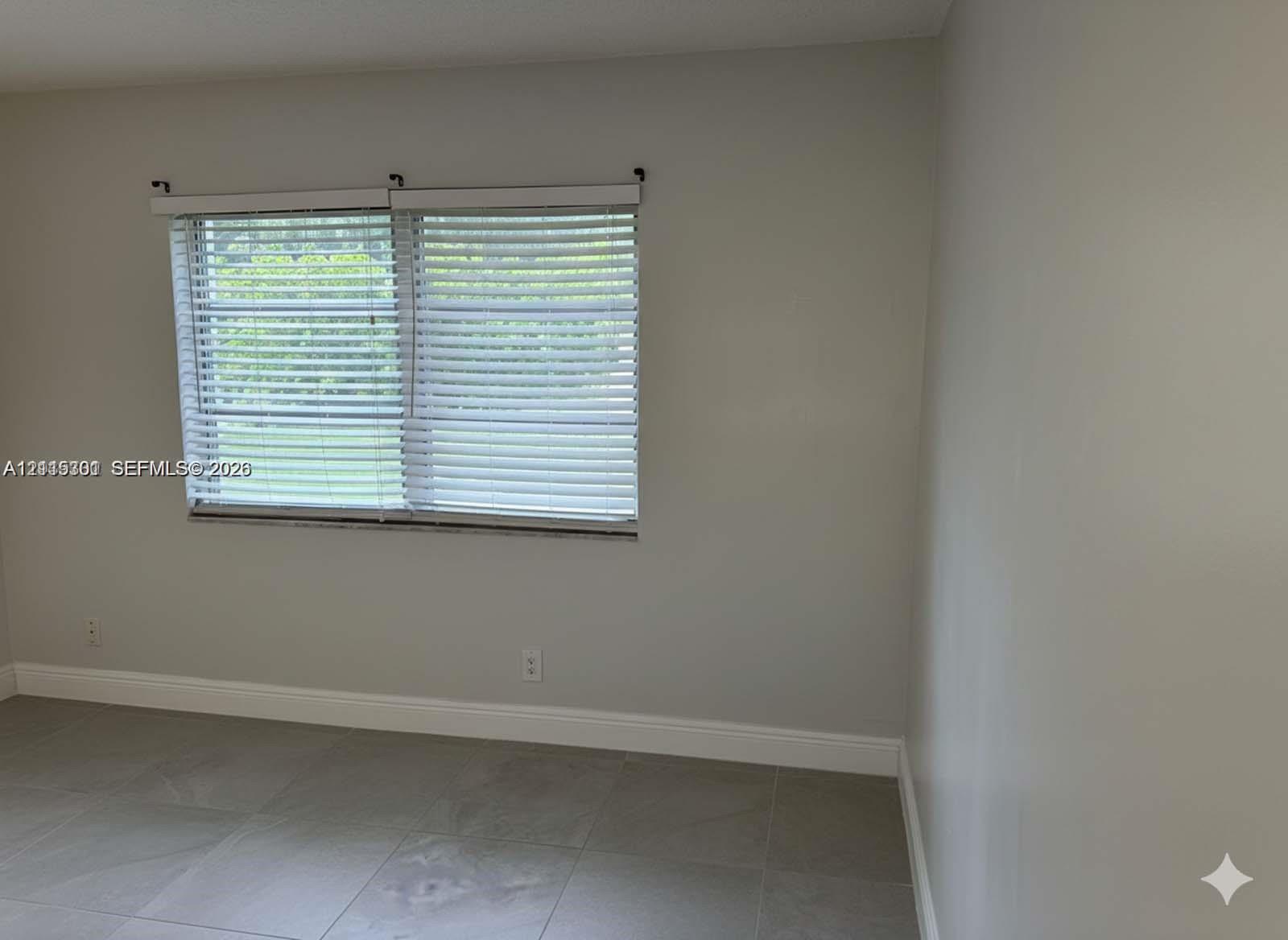 Neutral wall tones, oversized tile flooring, and horizontal window blinds