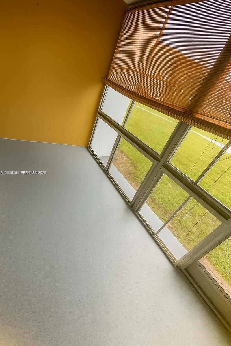 Enclosed balcony featuring multi-pane glass windows, neutral flooring, and yellow wall finishes