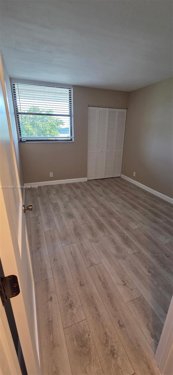Wood-finish flooring, horizontal slat window blinds, and white bifold closet doors