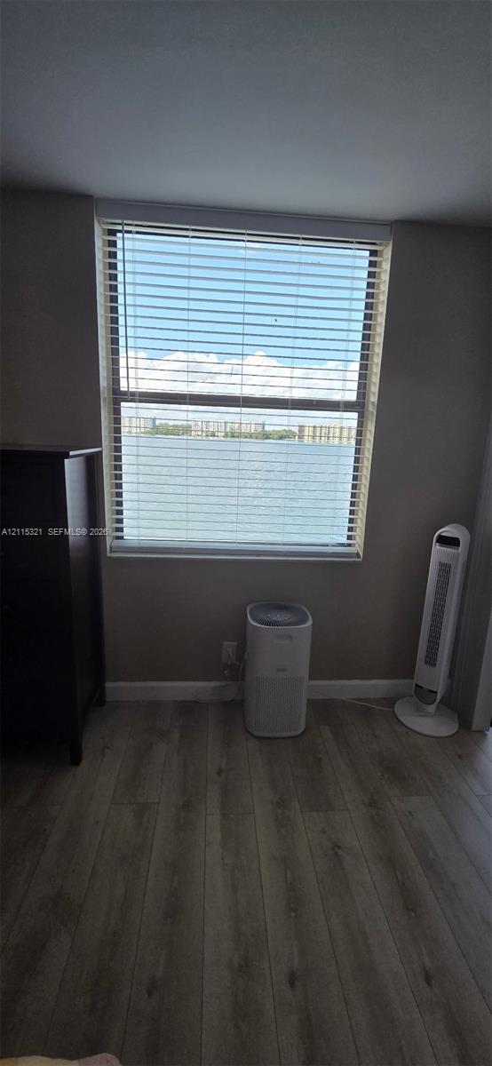Single-pane window with horizontal blinds featuring a water backdrop and wood-finish flooring