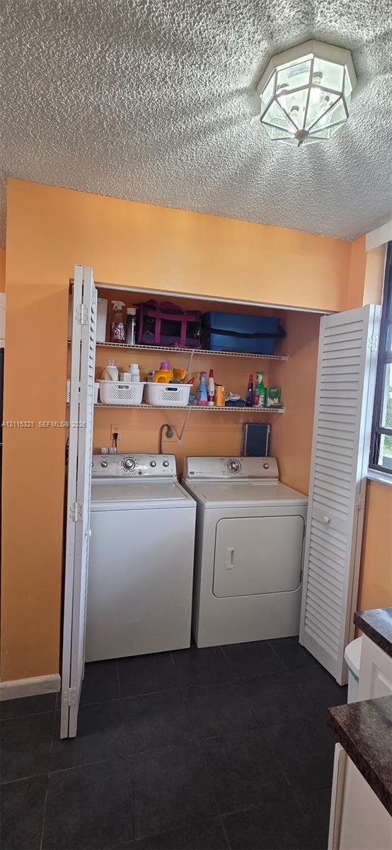 Laundry alcove featuring white louvered bifold doors, integrated metal shelving, and dark tile flooring
