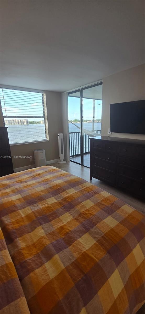 Floor-to-ceiling sliding glass doors opening to a balcony, water scenery, and neutral wall tones