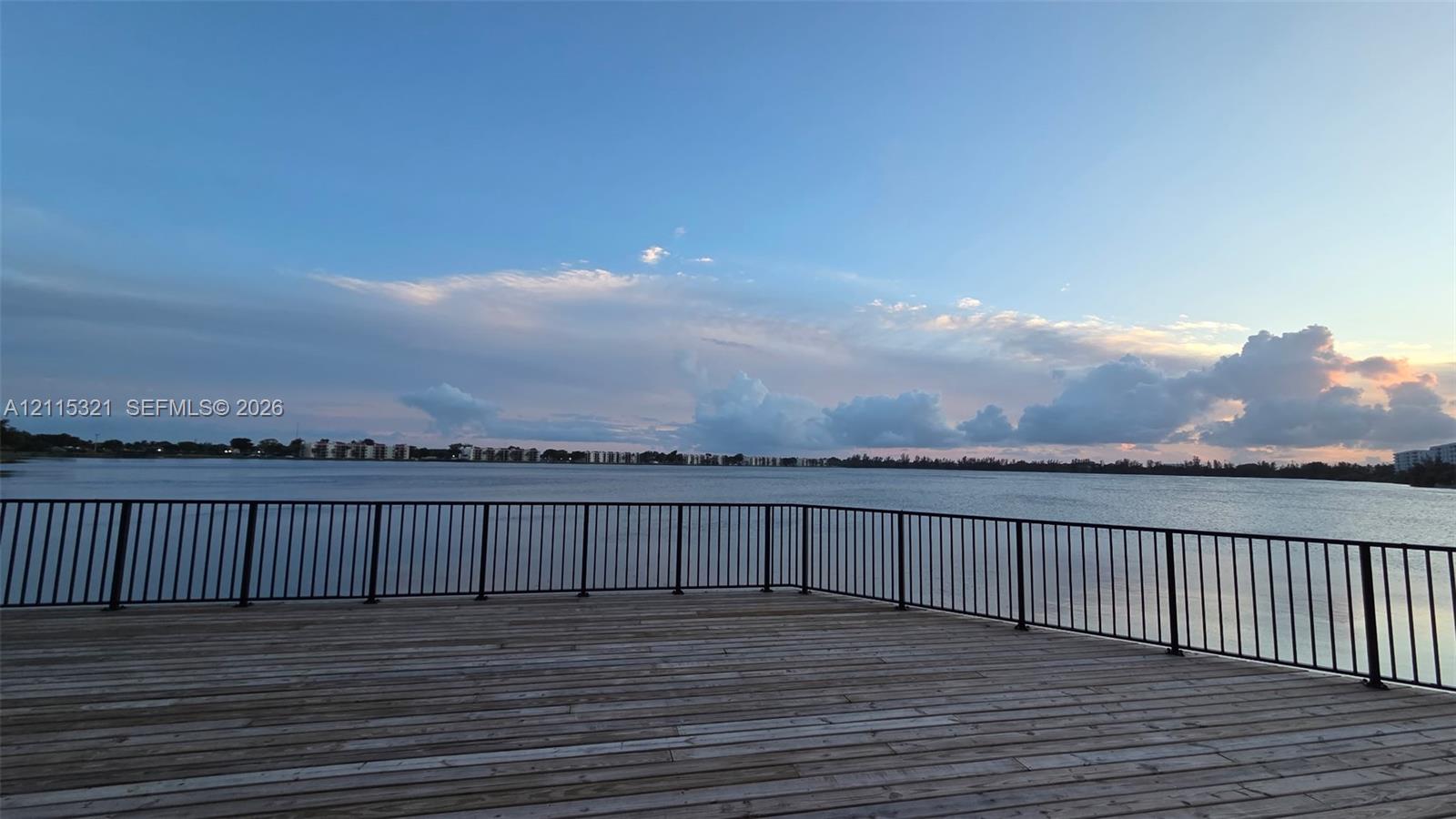 Wood-plank deck featuring a black metal railing overlooking the water