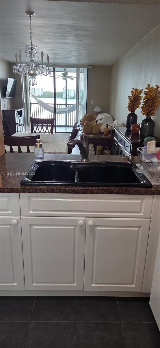 Kitchen featuring white shaker-style cabinetry, dark stone-finish countertops, and an integrated dual-basin sink with a metallic pull-down faucet